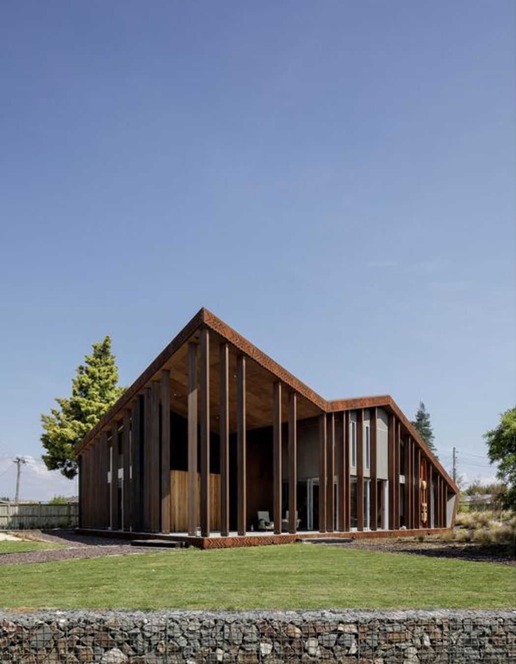 Look up to see a plywood-panelled soffit which features overlapping pattern work. Vertical columns are reminiscent of looking through tree trunks in a forest.