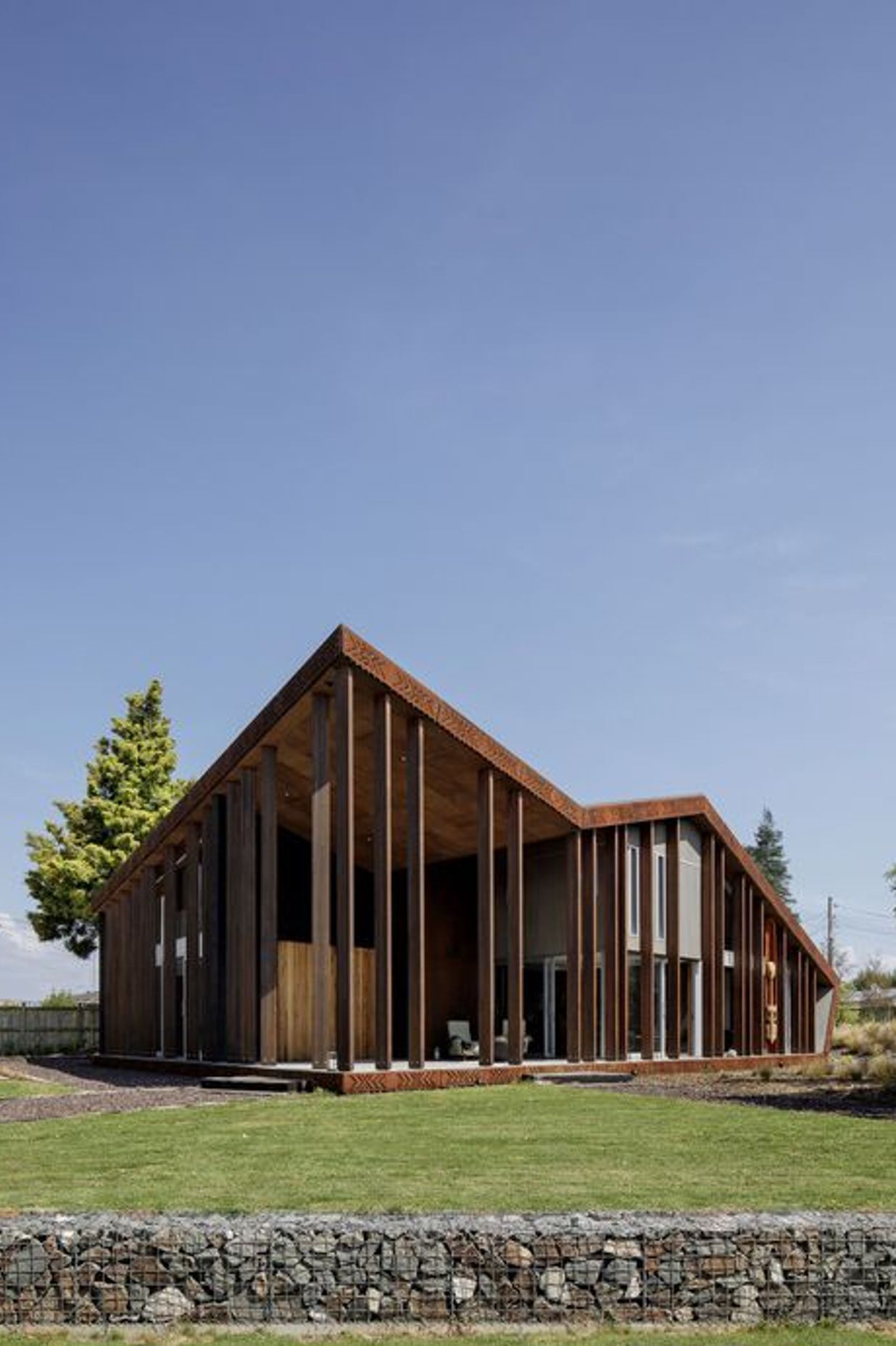 Look up to see a plywood-panelled soffit which features overlapping pattern work. Vertical columns are reminiscent of looking through tree trunks in a forest.