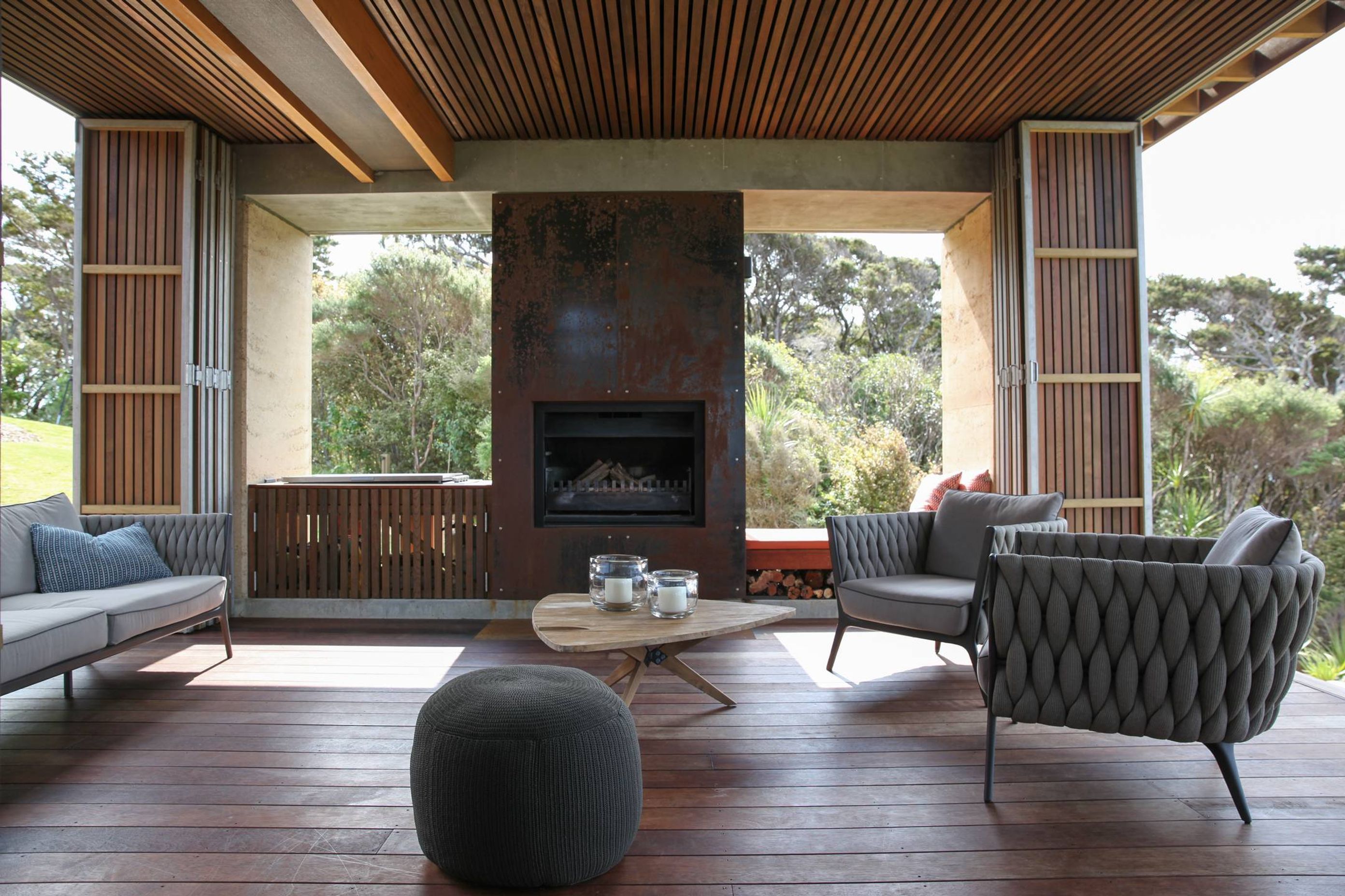 The outdoor room features cedar rainscreens, wide-plank spotted gum flooring and an open wood fire with metal surroundls. Photograph by Jackie Meiring.