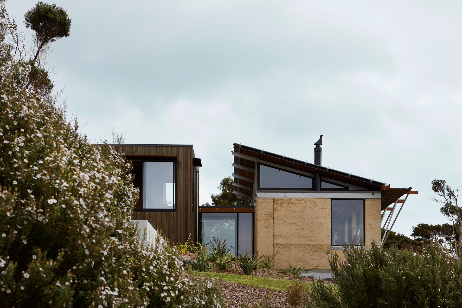 The two. forms are connected by a glazed walkway, with bedrooms in the buiding on the left and the living spaces in the building on the right of this house. Photograph by Jackie Meiring.