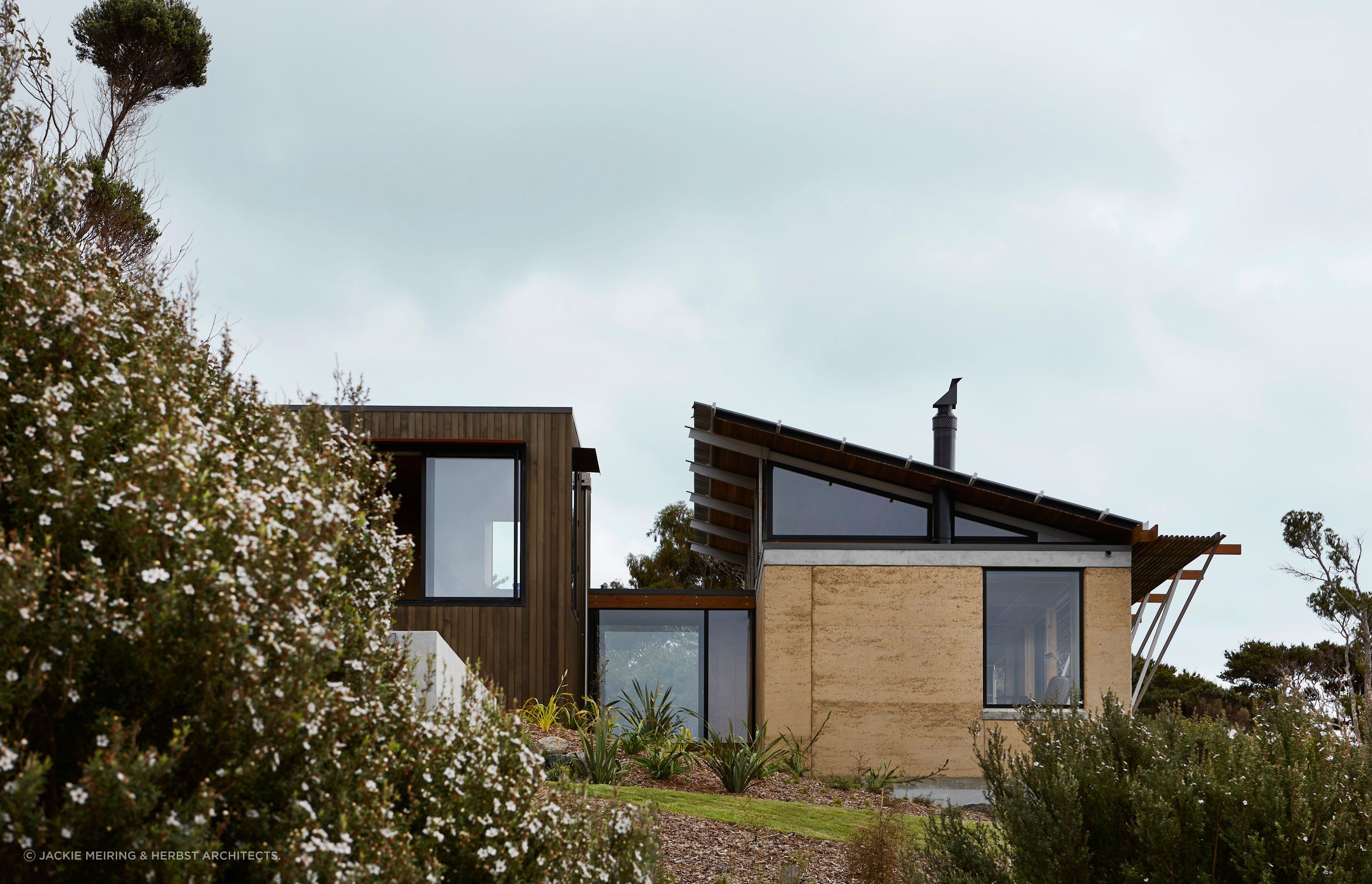 The two. forms are connected by a glazed walkway, with bedrooms in the buiding on the left and the living spaces in the building on the right of this house. Photograph by Jackie Meiring.