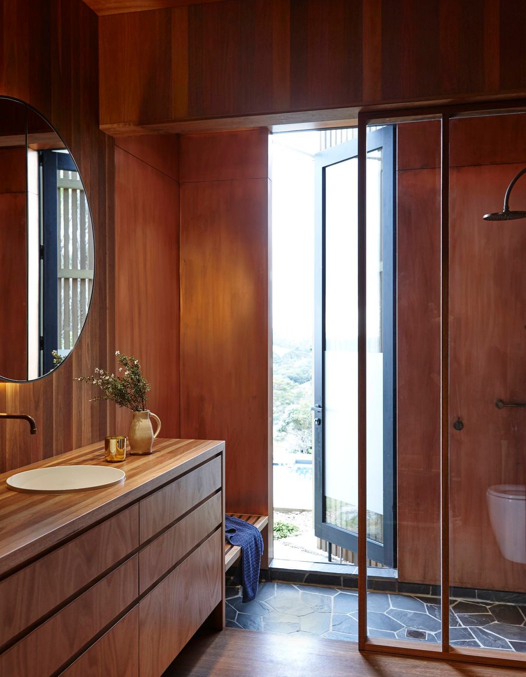 Basalt crazy paving on the shower floor provides a contrast to the timber interior.