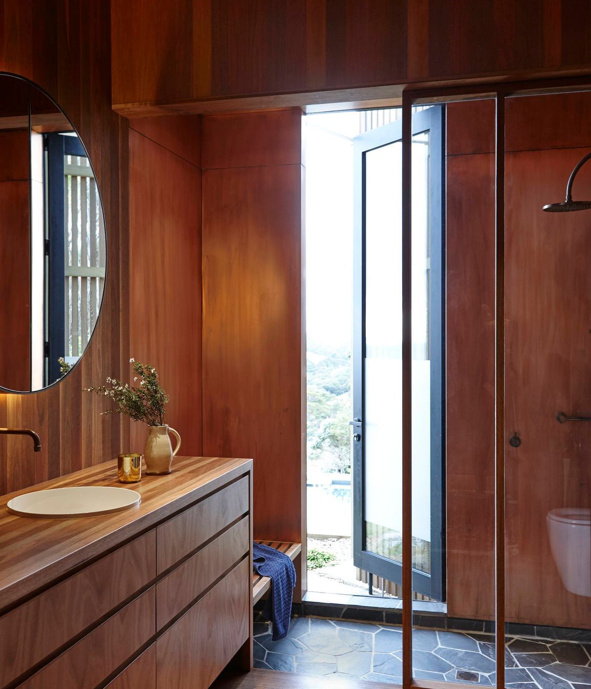 Basalt crazy paving on the shower floor provides a contrast to the timber interior.