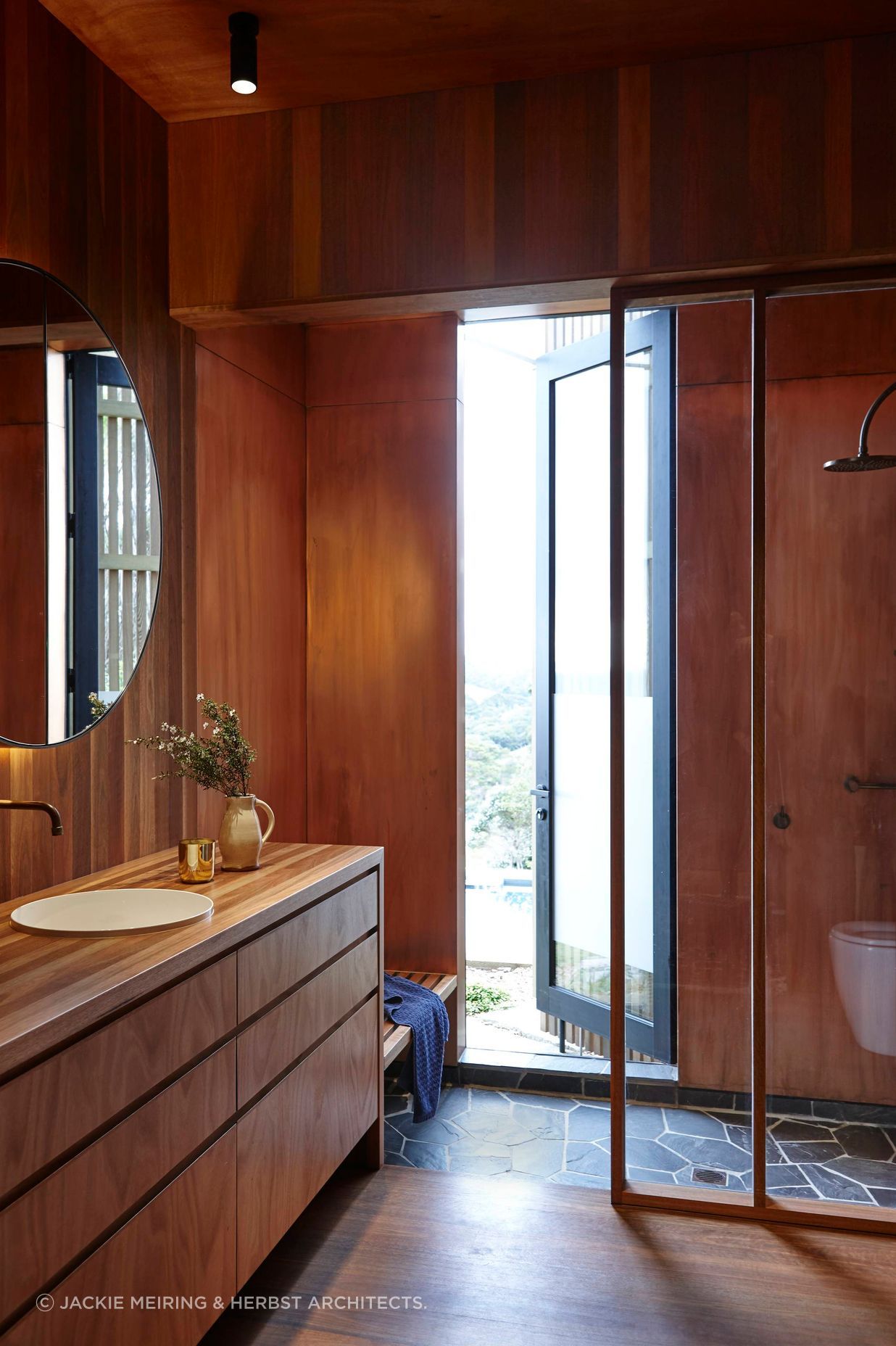 Basalt crazy paving on the shower floor provides a contrast to the timber interior.