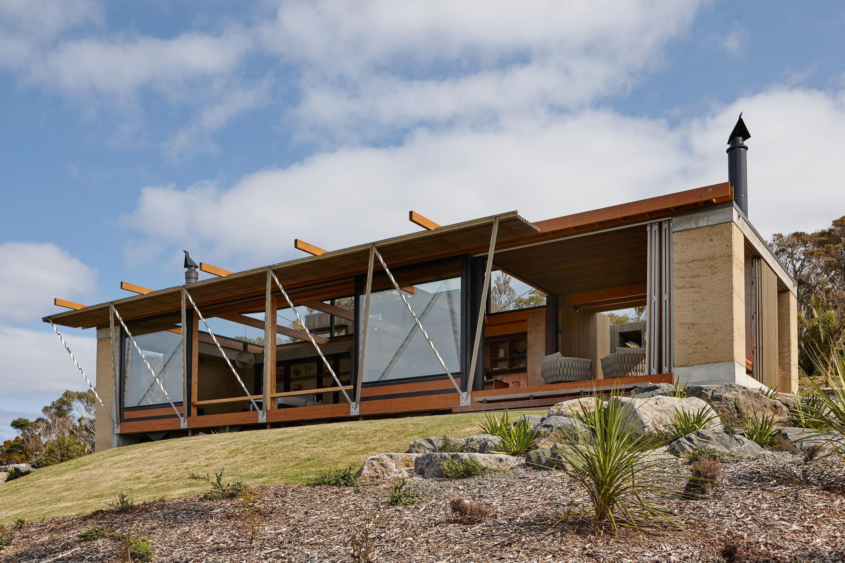 Rammed earth walls form bookends to the living spaces within this stunning home in Tutukaka by Herbst Architects. Photograph by Jackie Meiring.