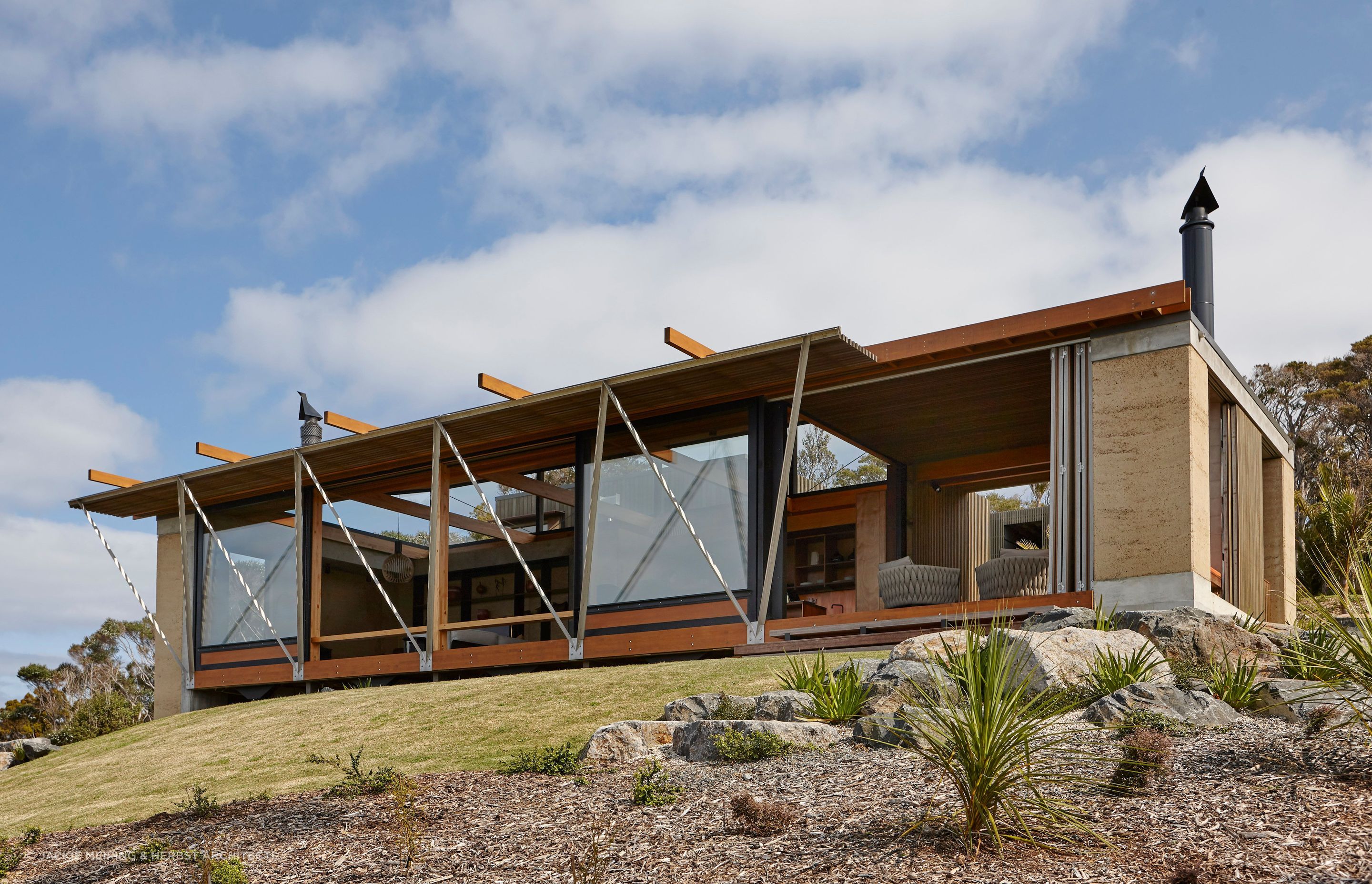 Rammed earth walls form bookends to the living spaces within this stunning home in Tutukaka by Herbst Architects. Photograph by Jackie Meiring.