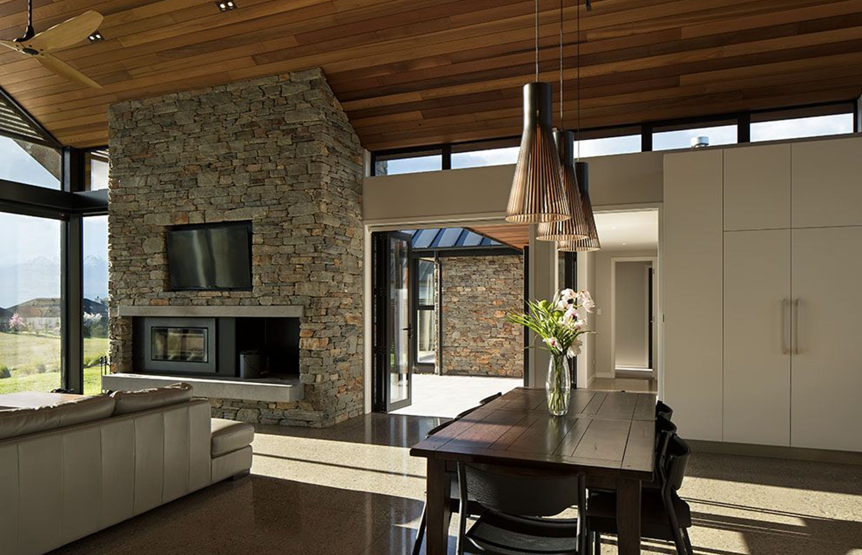 Much as the exterior form is reflected in the high volume interior spaces, so too is the external palette carried into the interior, with stonework and cedar featuring in the main living room.