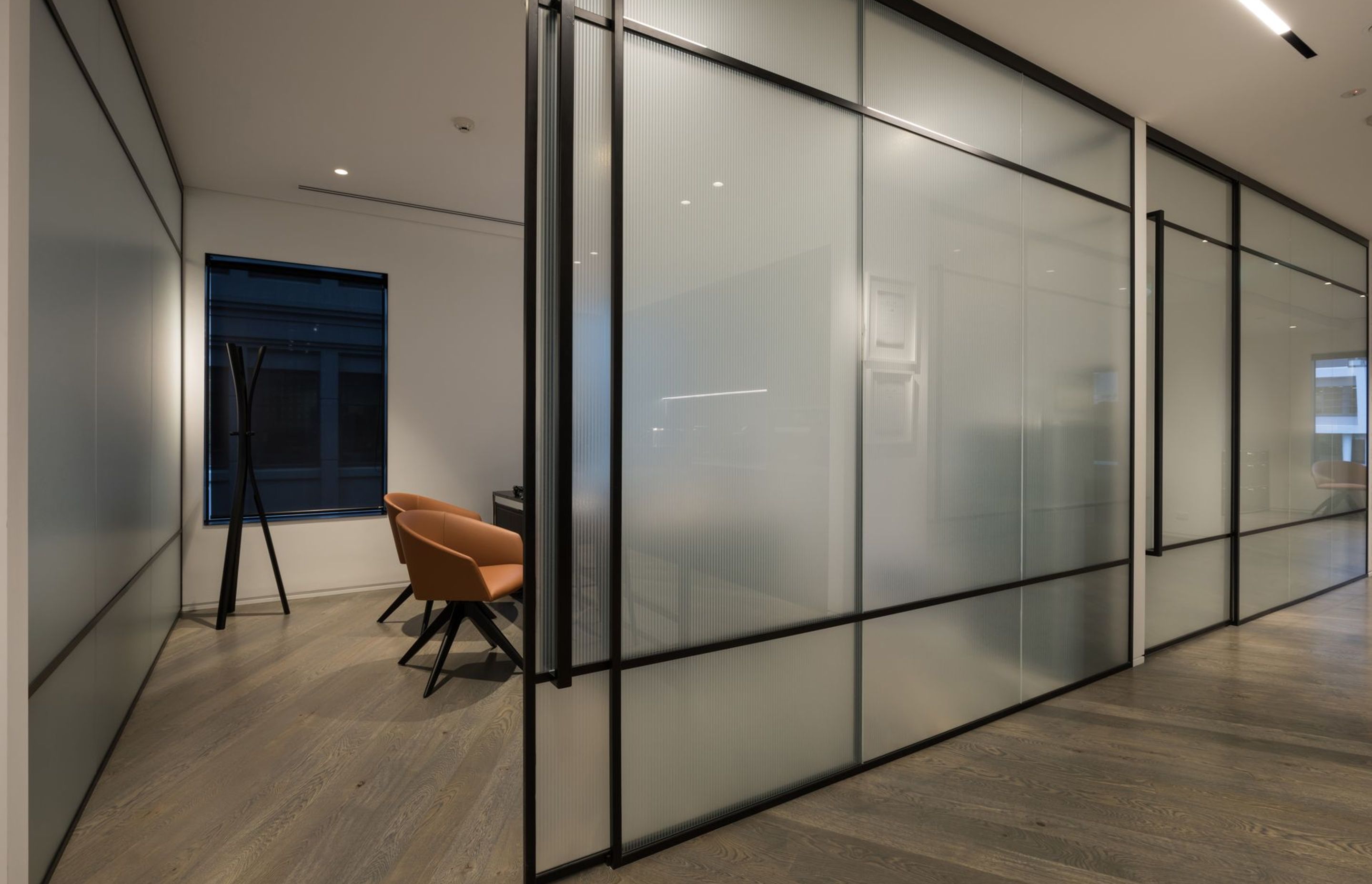 Office partition walls crafted in steel and reeded pattern glazing allowing perimeter natural loght to filter into circulation areas.
