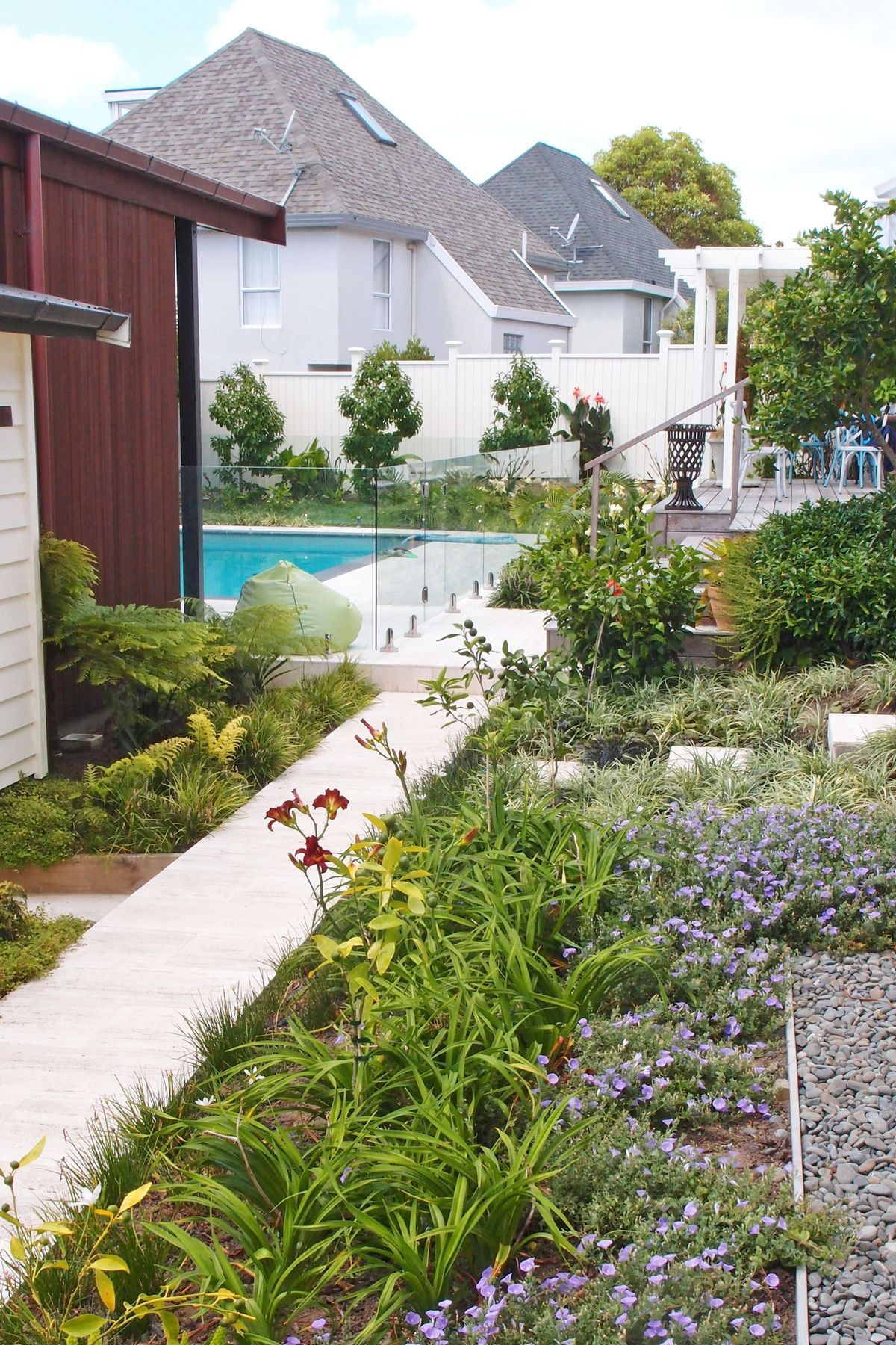 A stone tiled path leads through richly planted flowering borders to the rear garden pool courtyard