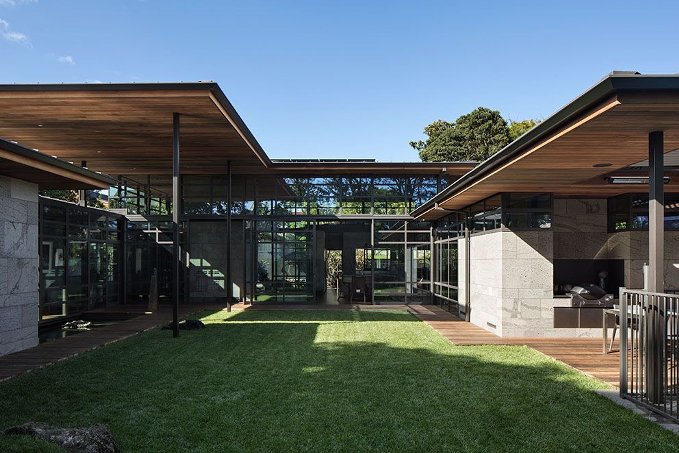 In the central courtyard, local stones (left) are featured within the landscape. Riverwood decked pathways run around the edges to the outdoor room and swimming pool (right).