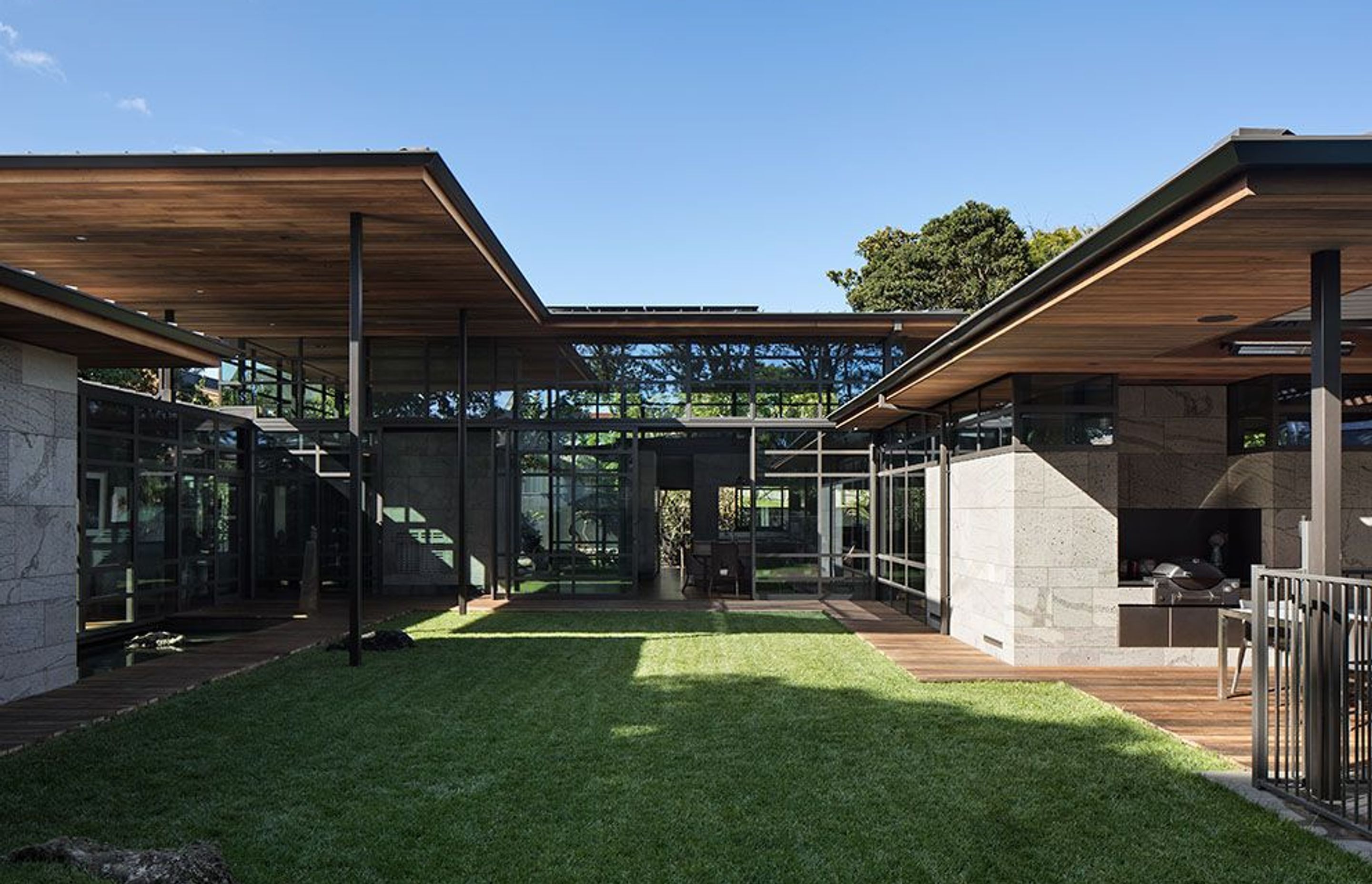 In the central courtyard, local stones (left) are featured within the landscape. Riverwood decked pathways run around the edges to the outdoor room and swimming pool (right).