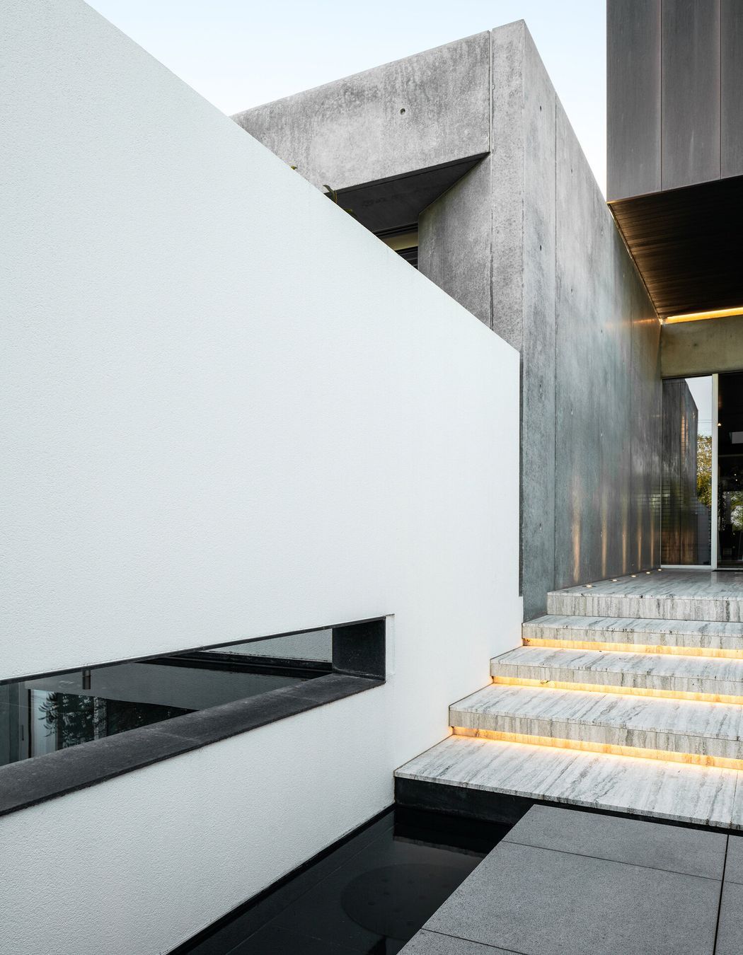 Copper and travertine surfaces are dressed between expressed structural elements of concrete and steel to create an enduring, timeless home.