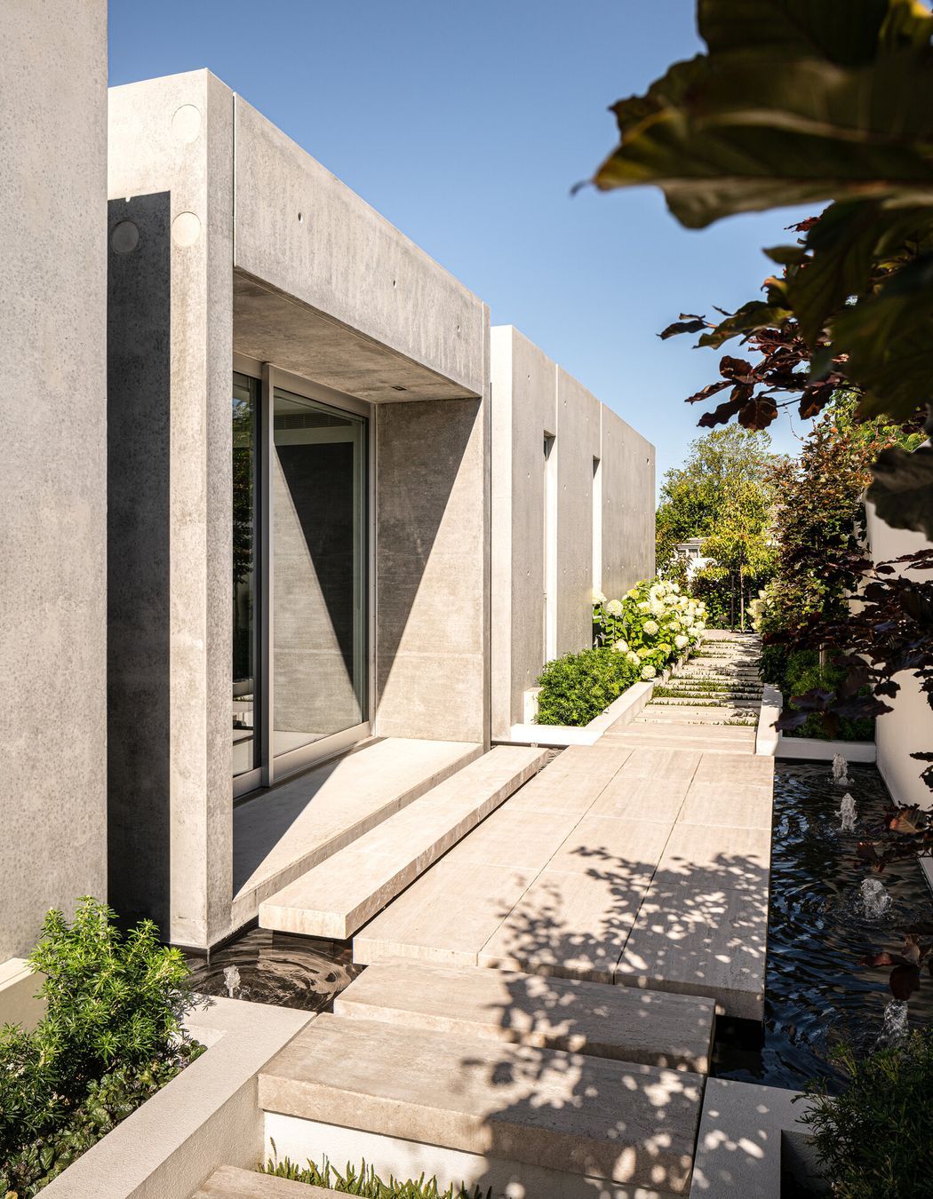 Natural elements—water and plants—soften the almost brutalist concrete forms creating a visual and aural counterpoint to the structure.