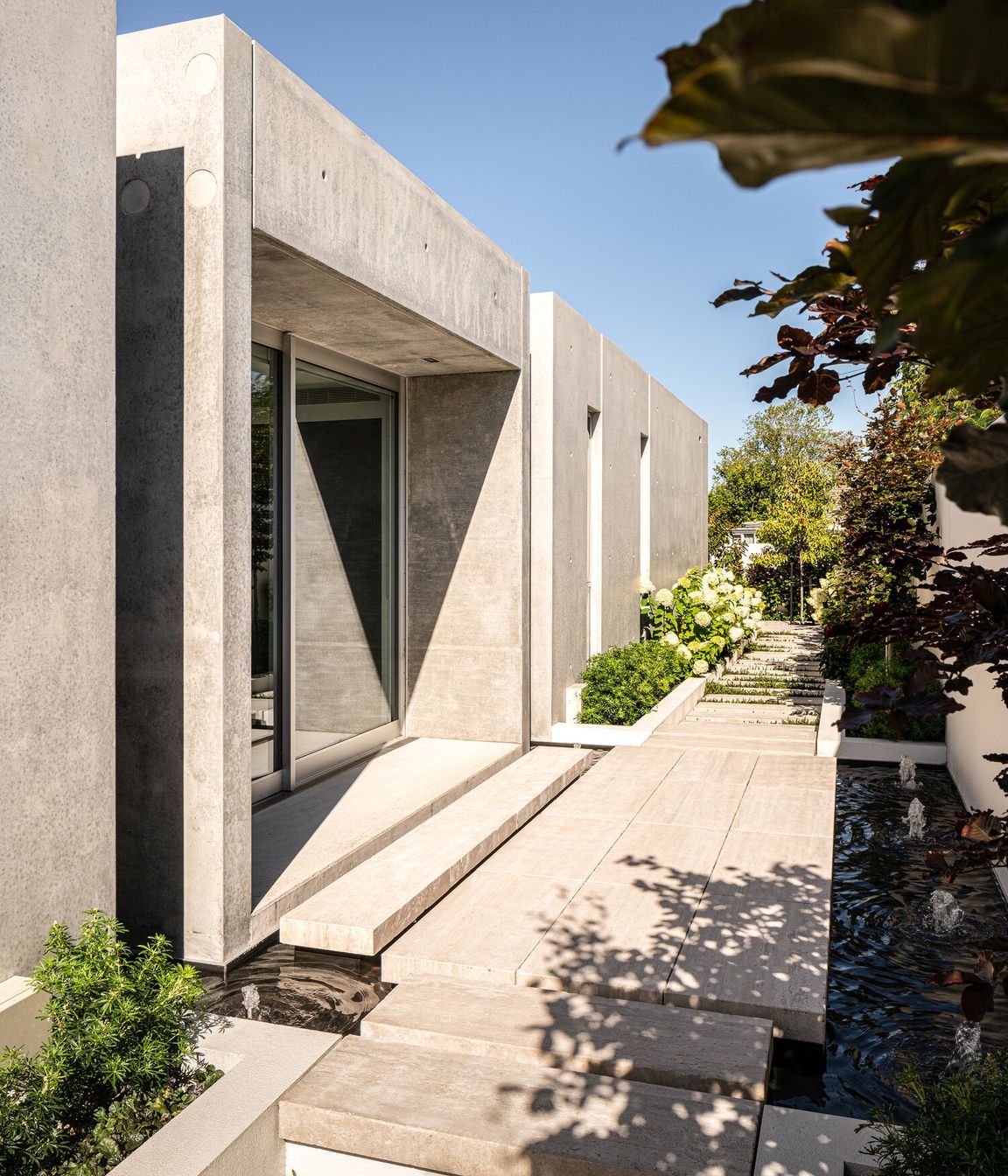 Natural elements—water and plants—soften the almost brutalist concrete forms creating a visual and aural counterpoint to the structure.