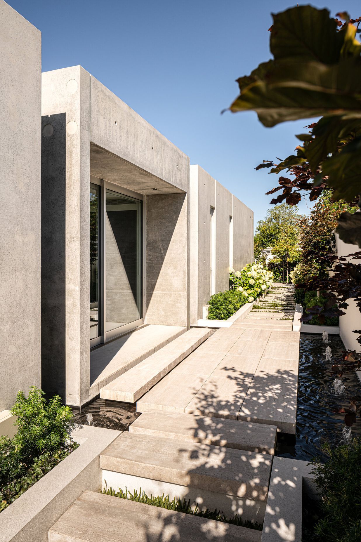 Natural elements—water and plants—soften the almost brutalist concrete forms creating a visual and aural counterpoint to the structure.