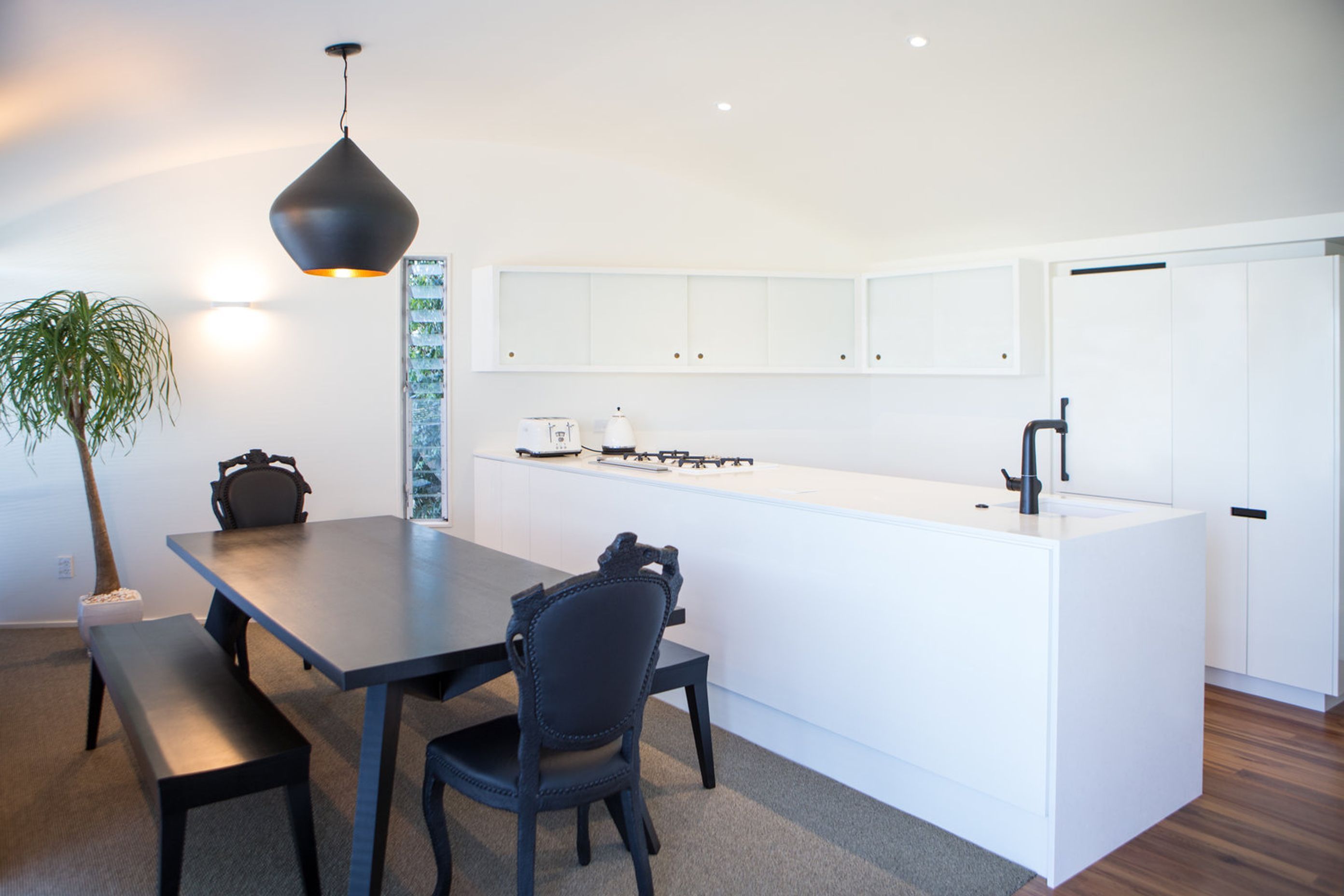 Contemporary black dining table and chairs and pendant light off-sets the classic white kitchen design.