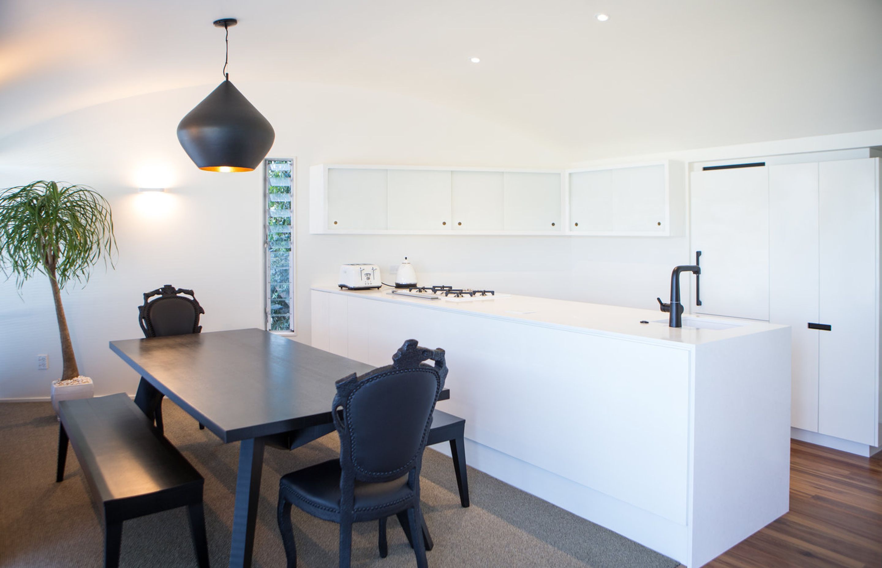 Contemporary black dining table and chairs and pendant light off-sets the classic white kitchen design.