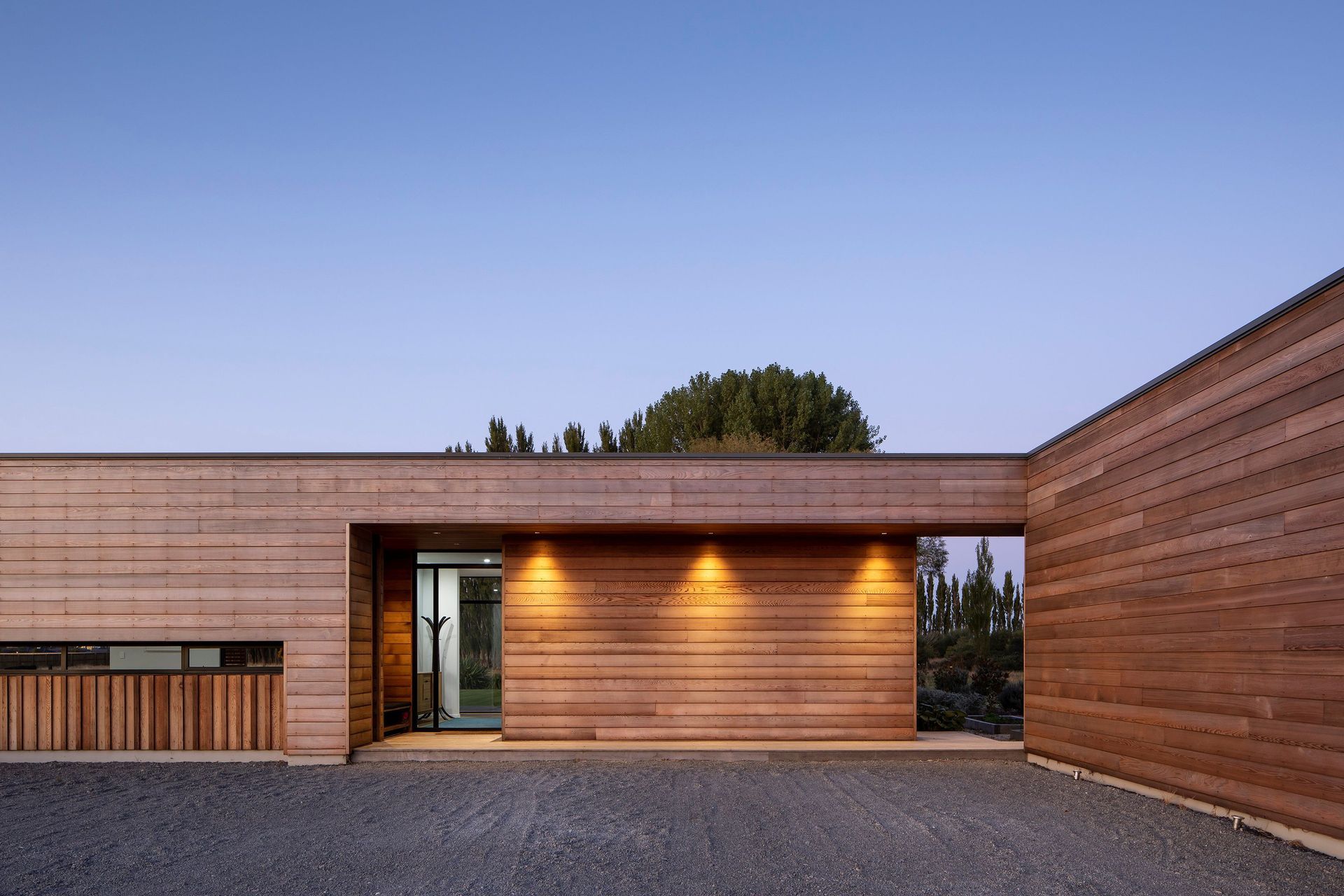 Facing south-west, the recessed entry has a covered walkway leading to the garage on the right. Built-in seating/storage in the porch operates like a mudroom.