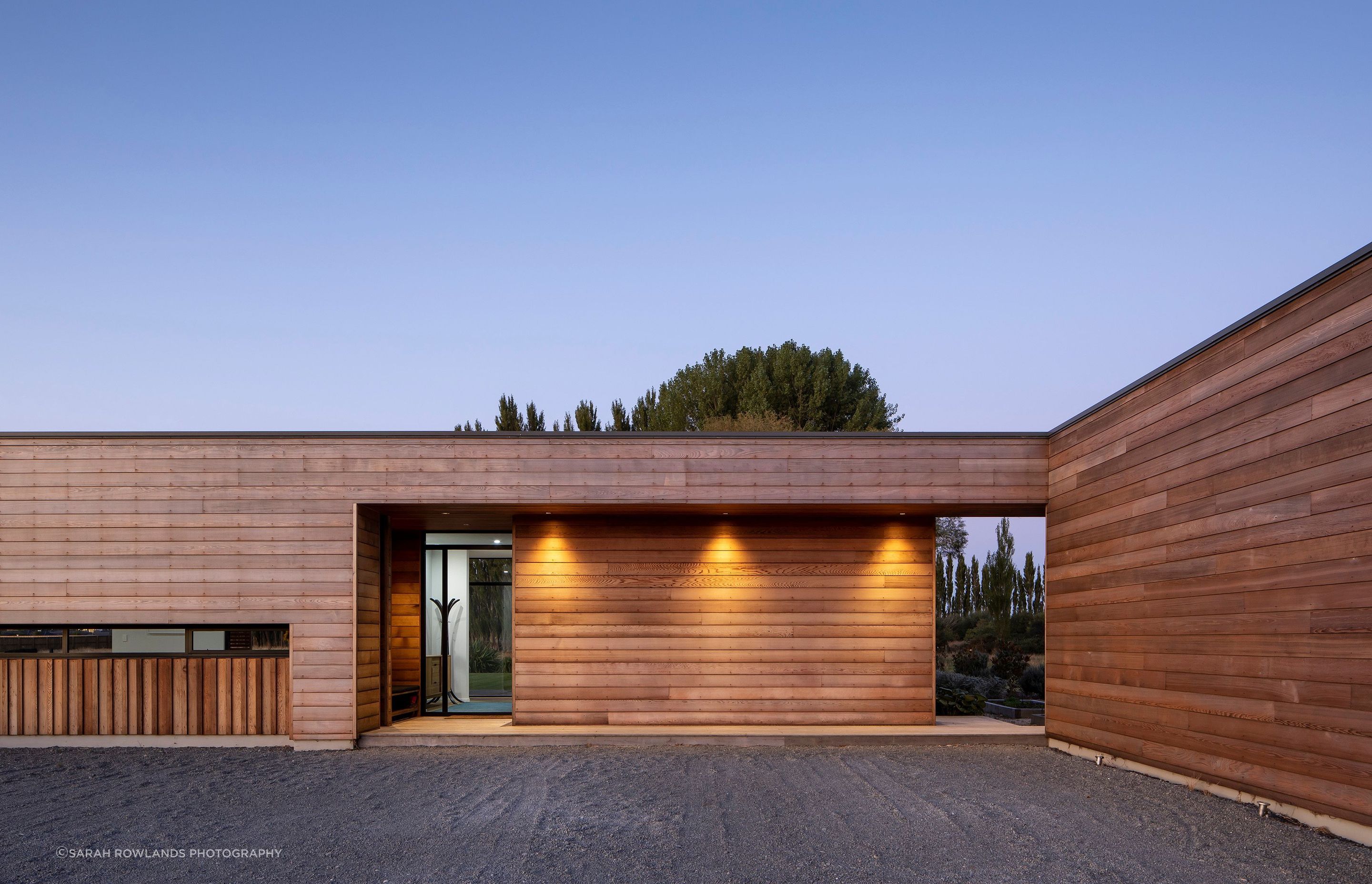 Facing south-west, the recessed entry has a covered walkway leading to the garage on the right. Built-in seating/storage in the porch operates like a mudroom.