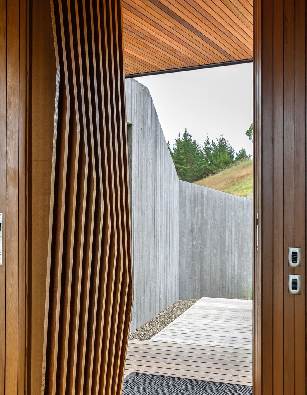 The faceted cedar fins on the main entry door each have a slighty different angle, playing on the vertical in situ formwork pattern of the spine entry wall.