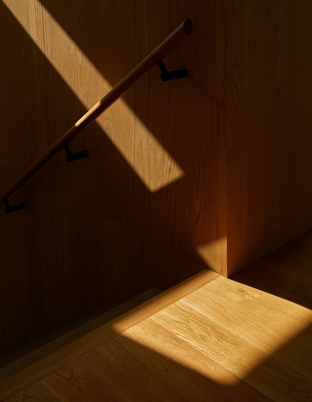 American oak lines the stairwell, adding a warm contrast to the concrete details.