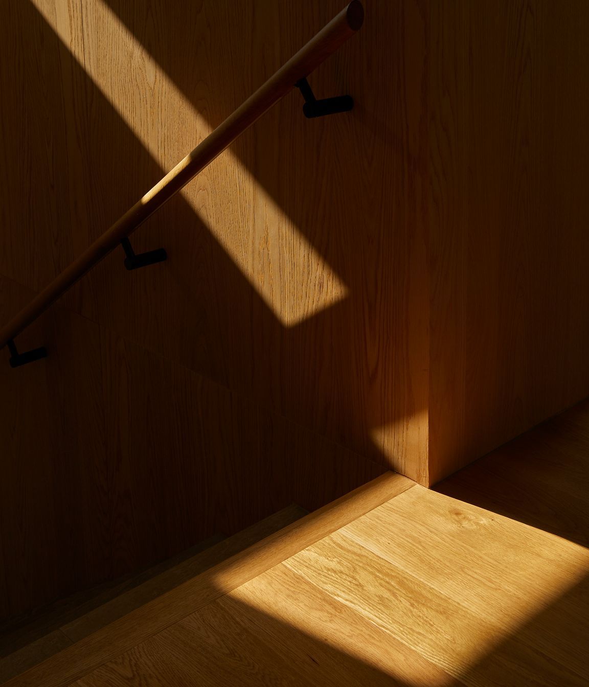 American oak lines the stairwell, adding a warm contrast to the concrete details.