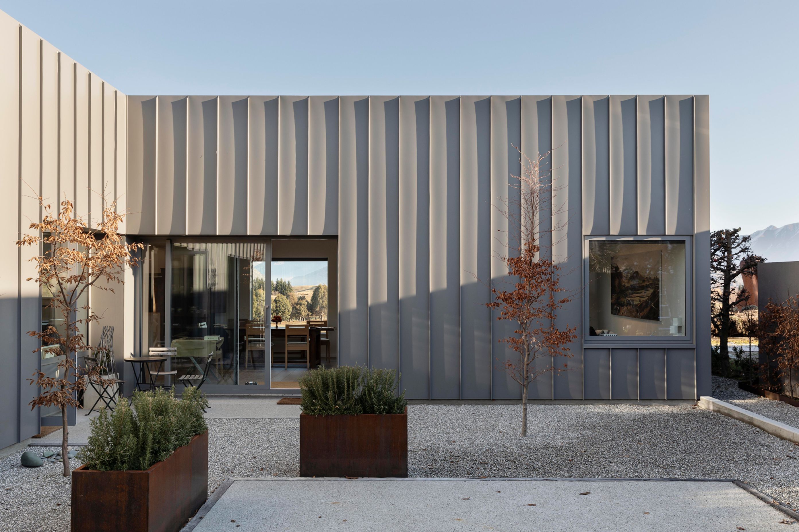 The sheltered extenal courtyard has an almost Mediterranean feel, with pale shingle and copper boxed planters.