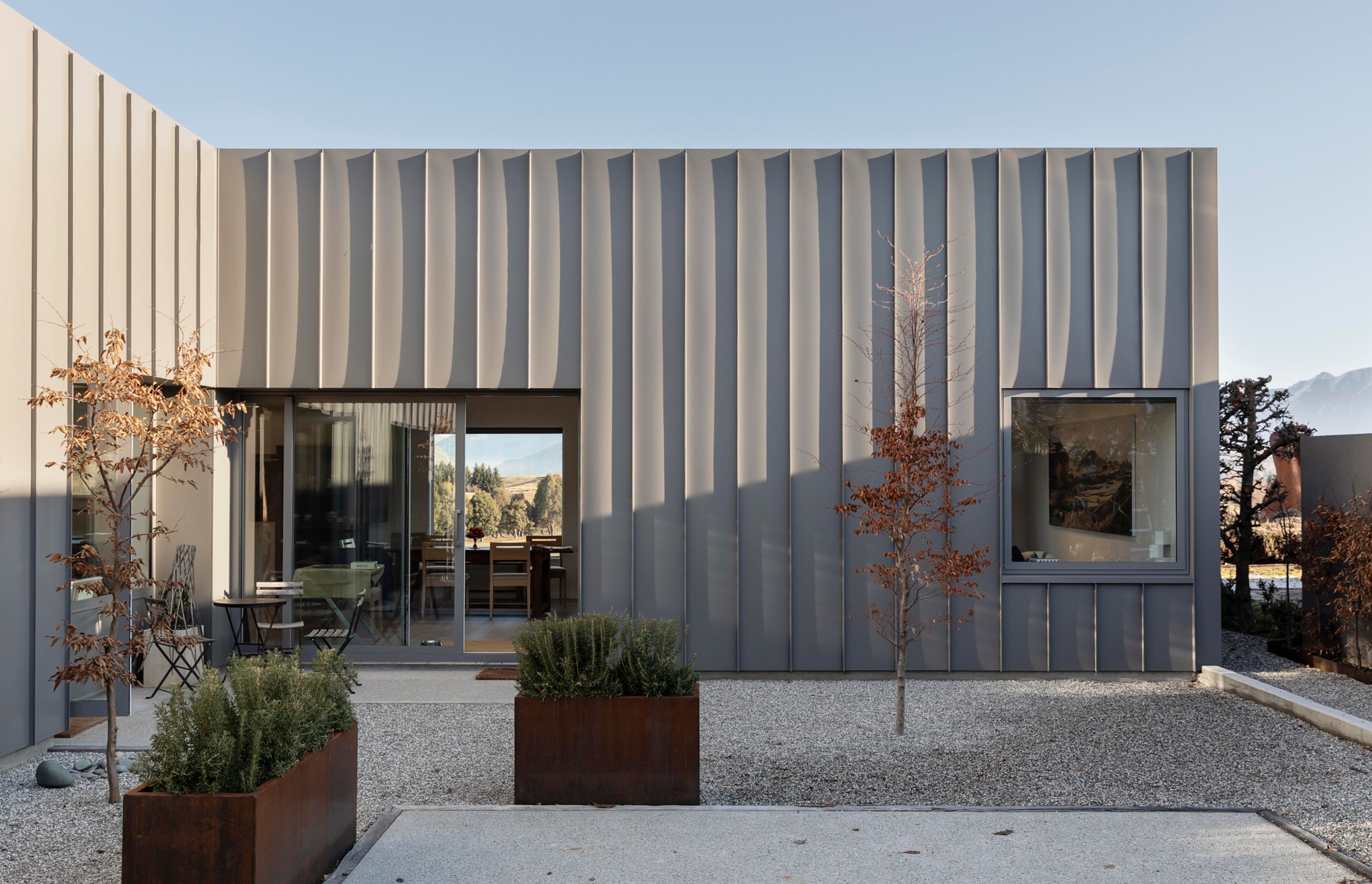 The sheltered extenal courtyard has an almost Mediterranean feel, with pale shingle and copper boxed planters.