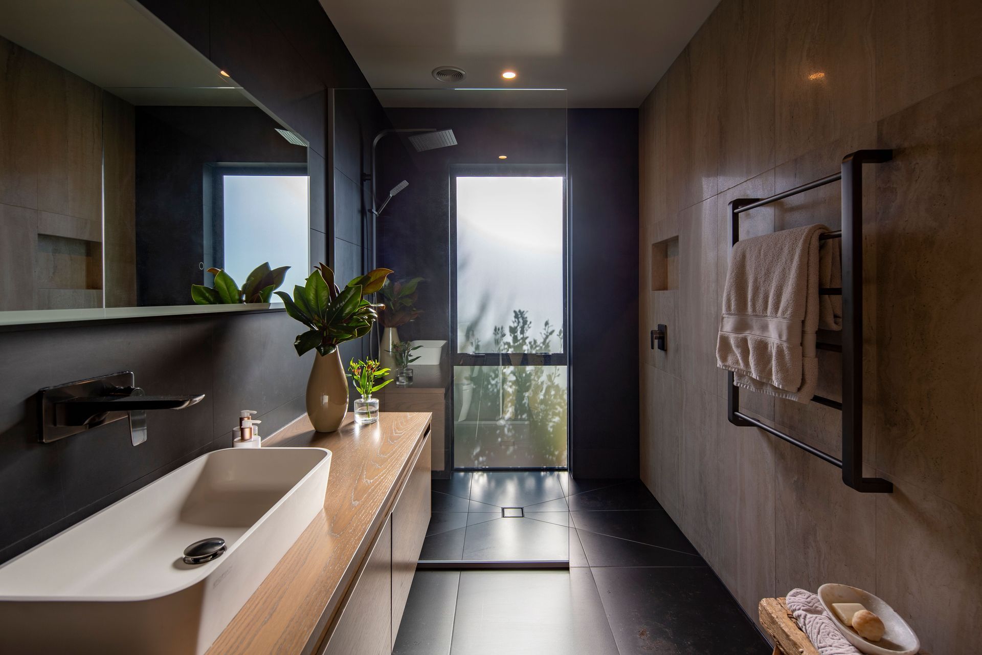 Dark tiling and a walk-in shower feature in the main bathroom.