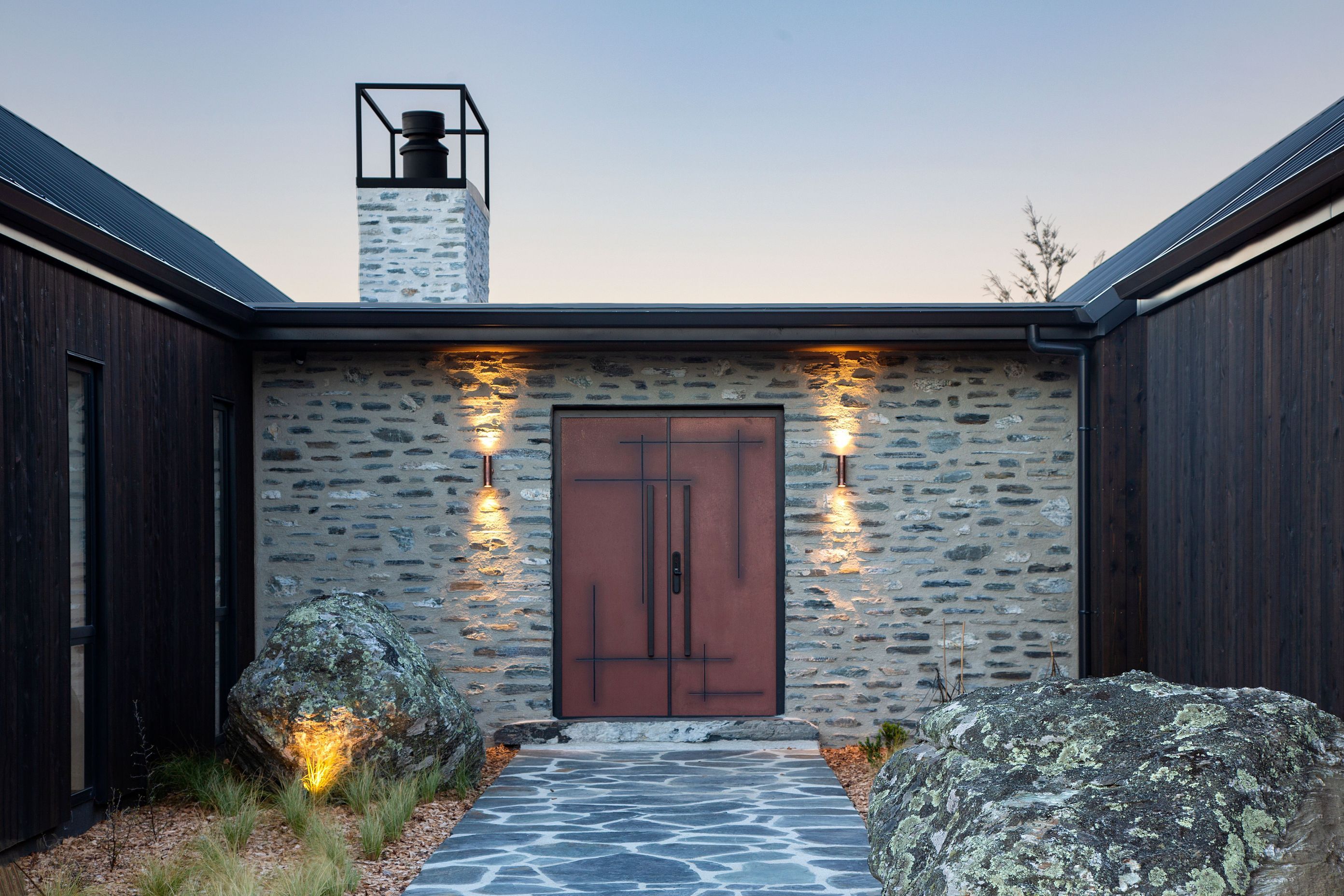 A statement corten front door offers a warm welcome to the home.
