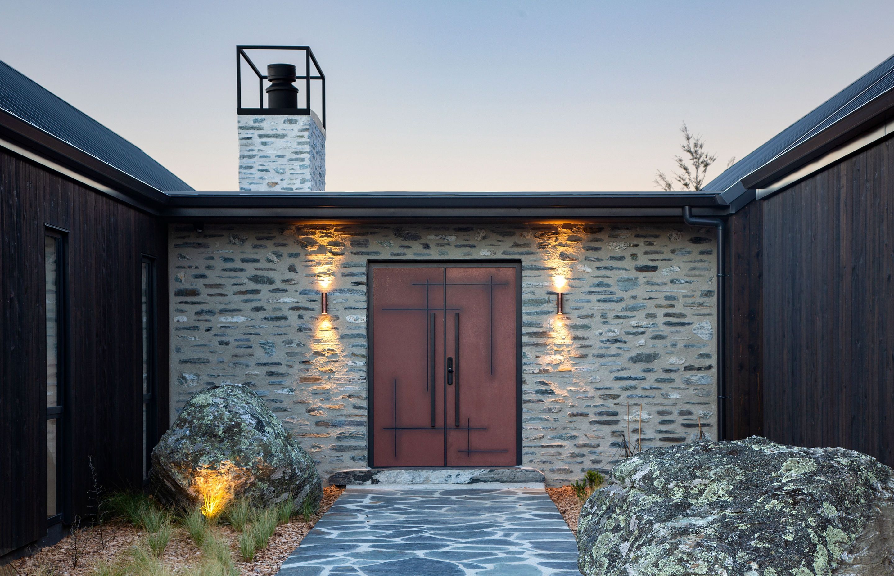 A statement corten front door offers a warm welcome to the home.
