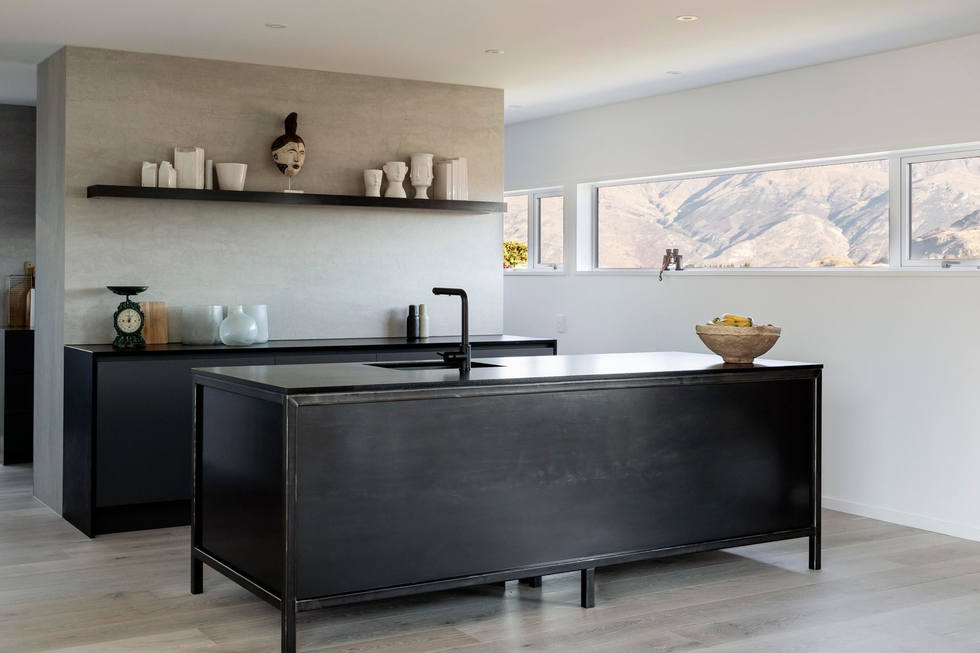 The bold, dark kitchen features cabinetry that looks like furniture placed into the space.