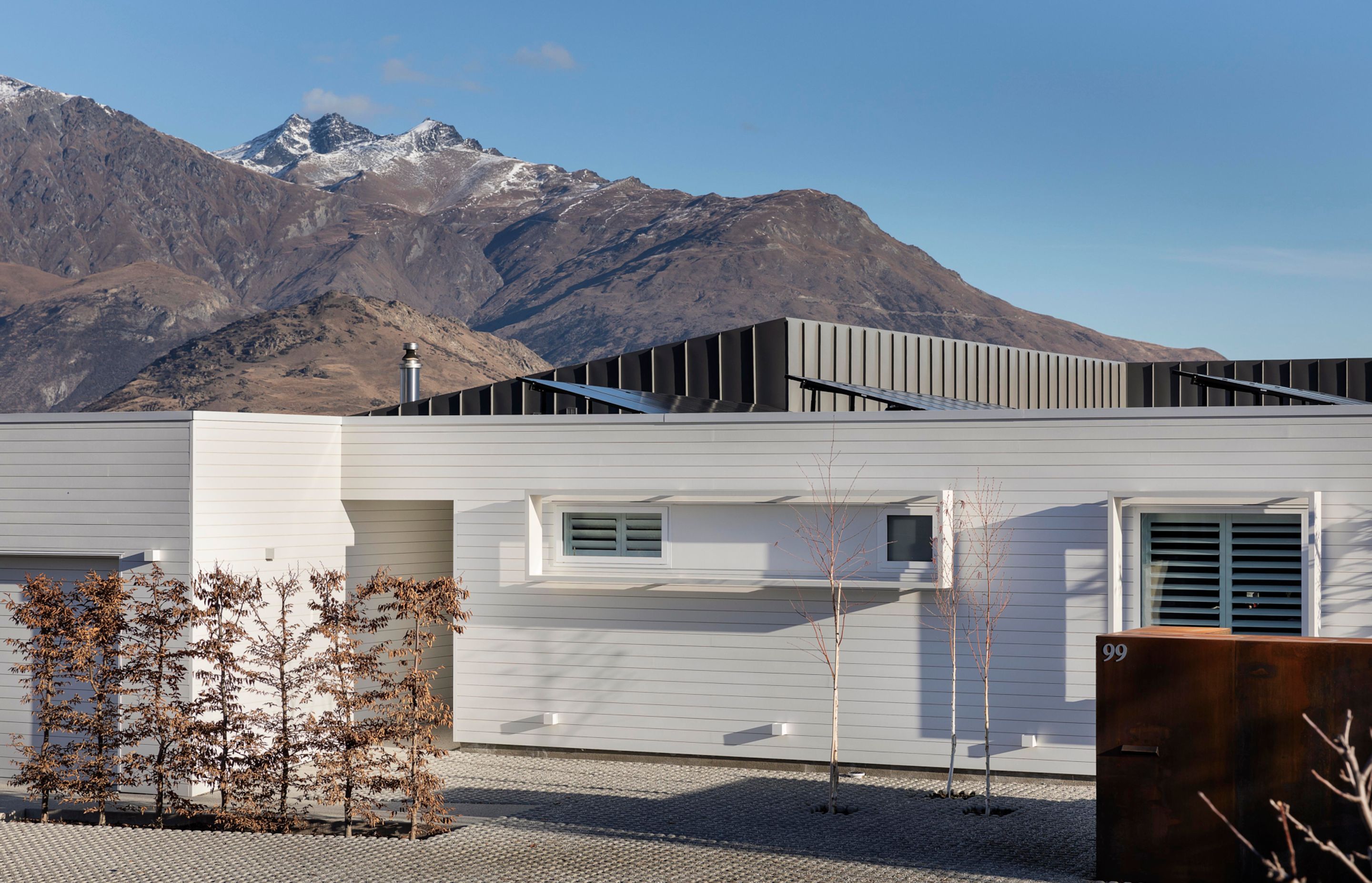 The street frontage shows the rooflines of the back of the house imitating the mountains in the background.