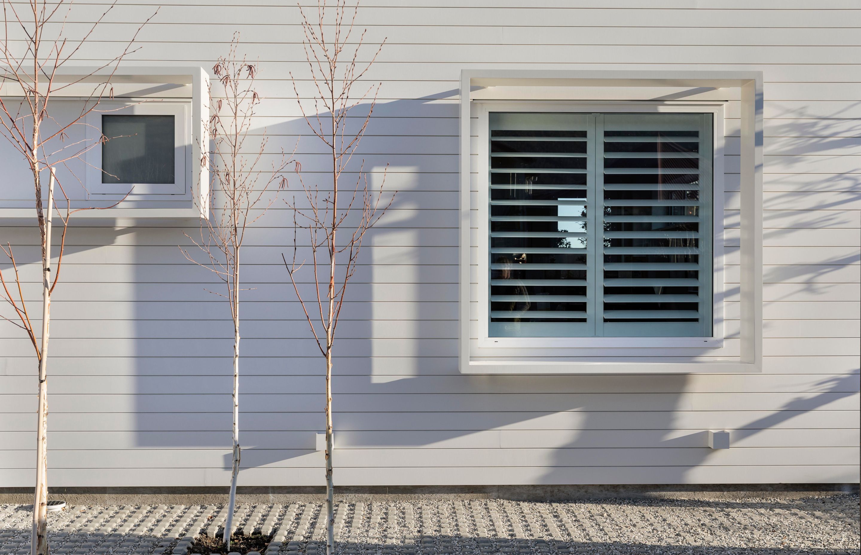 The glazing on the white section of the home is framed with protruding box frames that almost look as if they are floating.