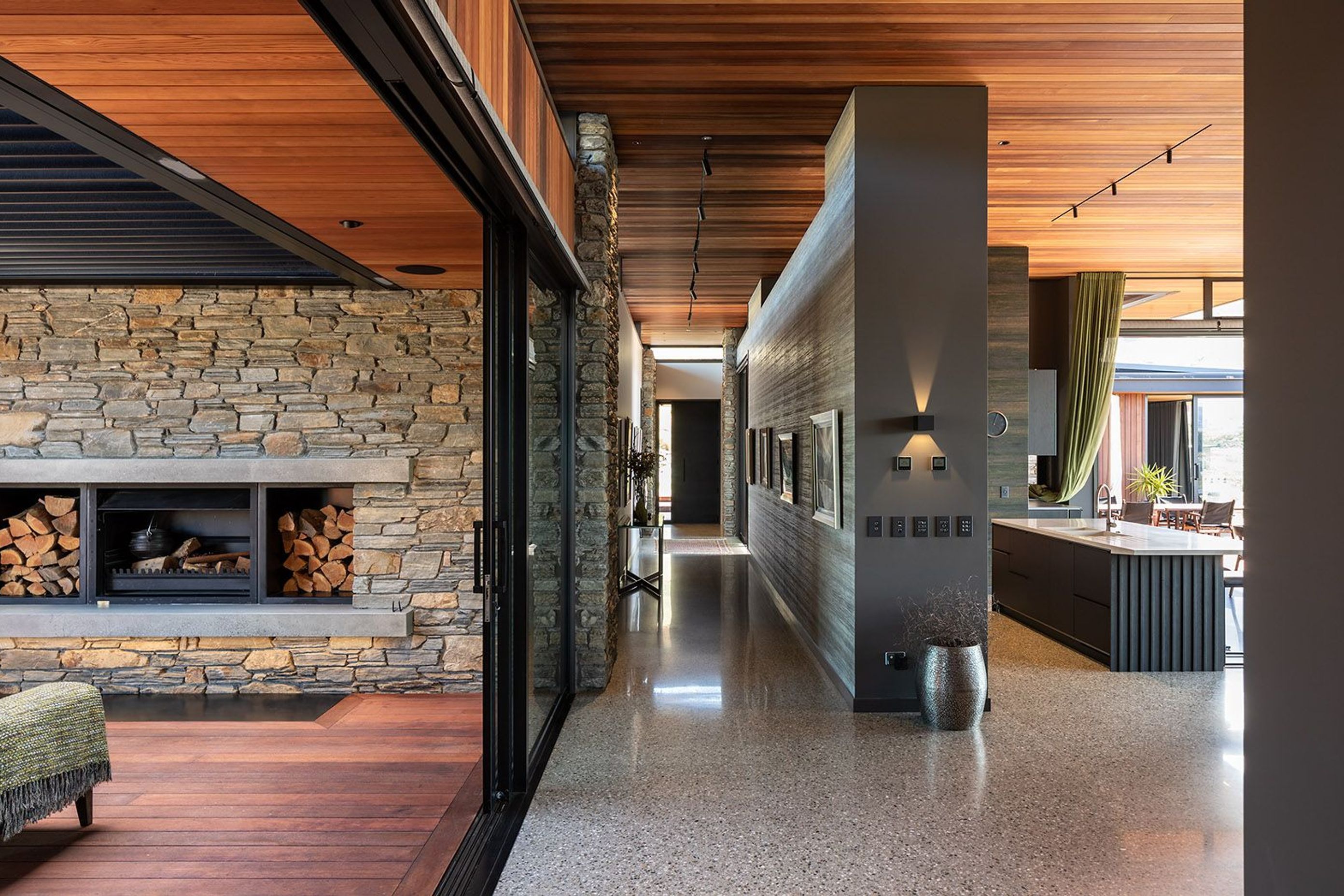 A central gallery wall leading from the entryway to the living space is finished in a textured wallpaper that is reminiscent of concrete.