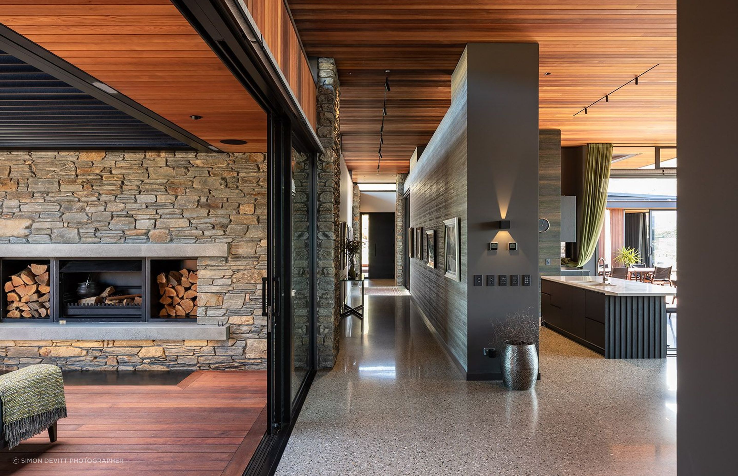 A central gallery wall leading from the entryway to the living space is finished in a textured wallpaper that is reminiscent of concrete.