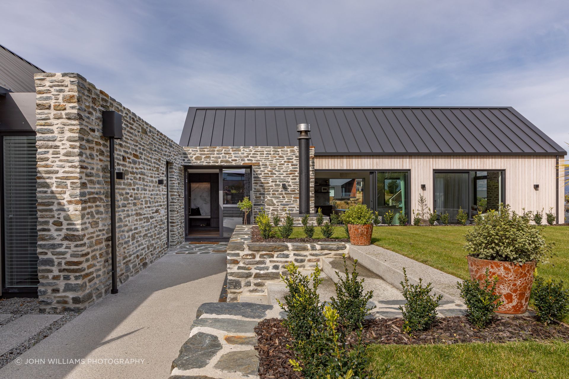 Bagged schist stone walls lead visitors to the main entry