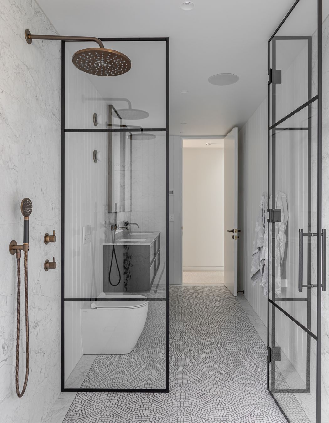 Generous airy bathrooms are tiled in a fan pattern with light marble mosaic