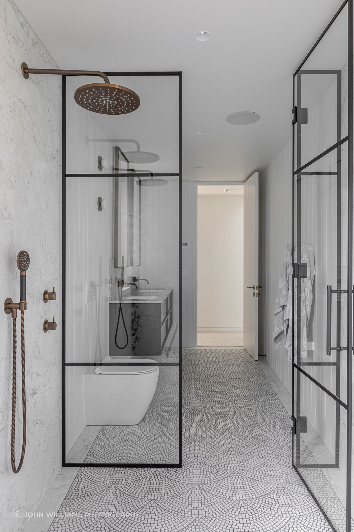 Generous airy bathrooms are tiled in a fan pattern with light marble mosaic