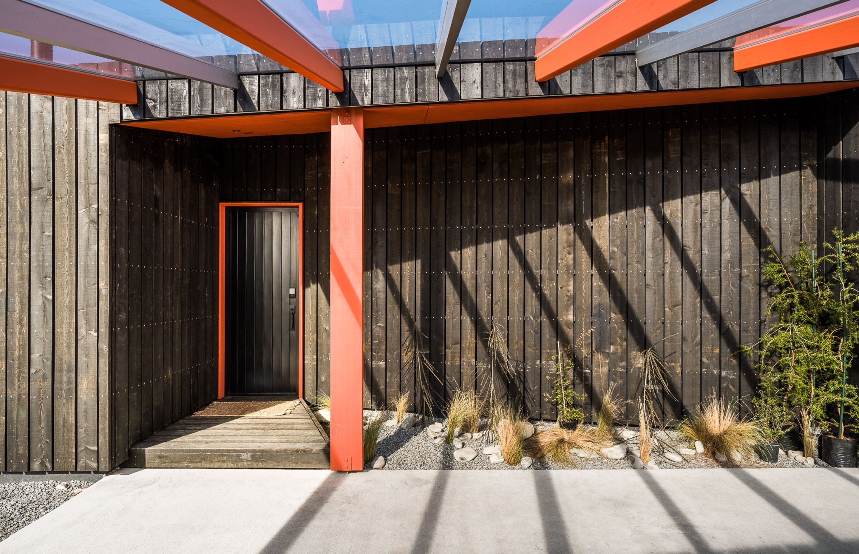 A series of burnt orange structural frames extending down from the cabin roofline, lend a sense of spaciousness to the overall design without increasing the permitted footprint.