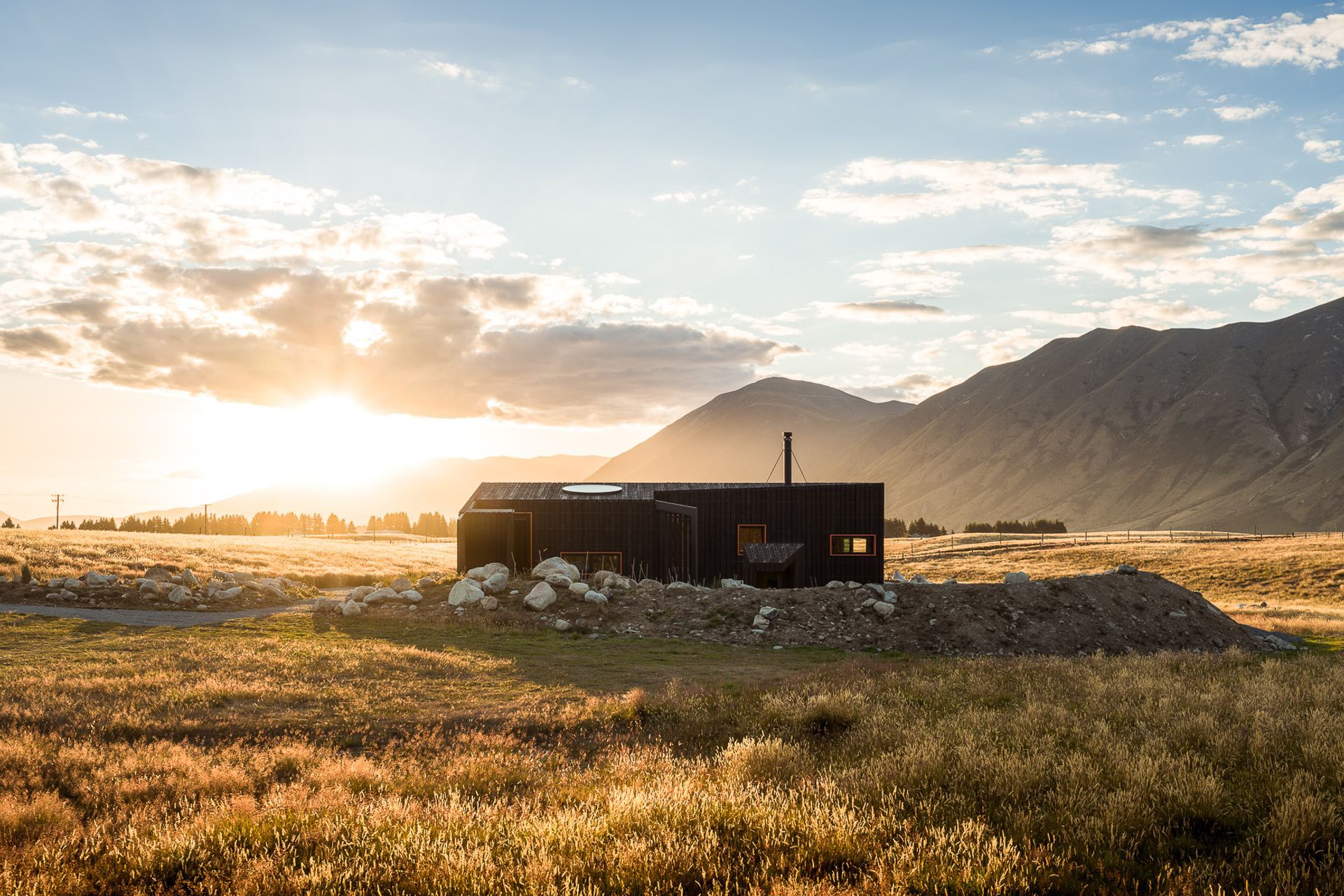 Natural stone boulders—reclaimed from the site excavation—were used to create a nested plinth on which the cabin perches.