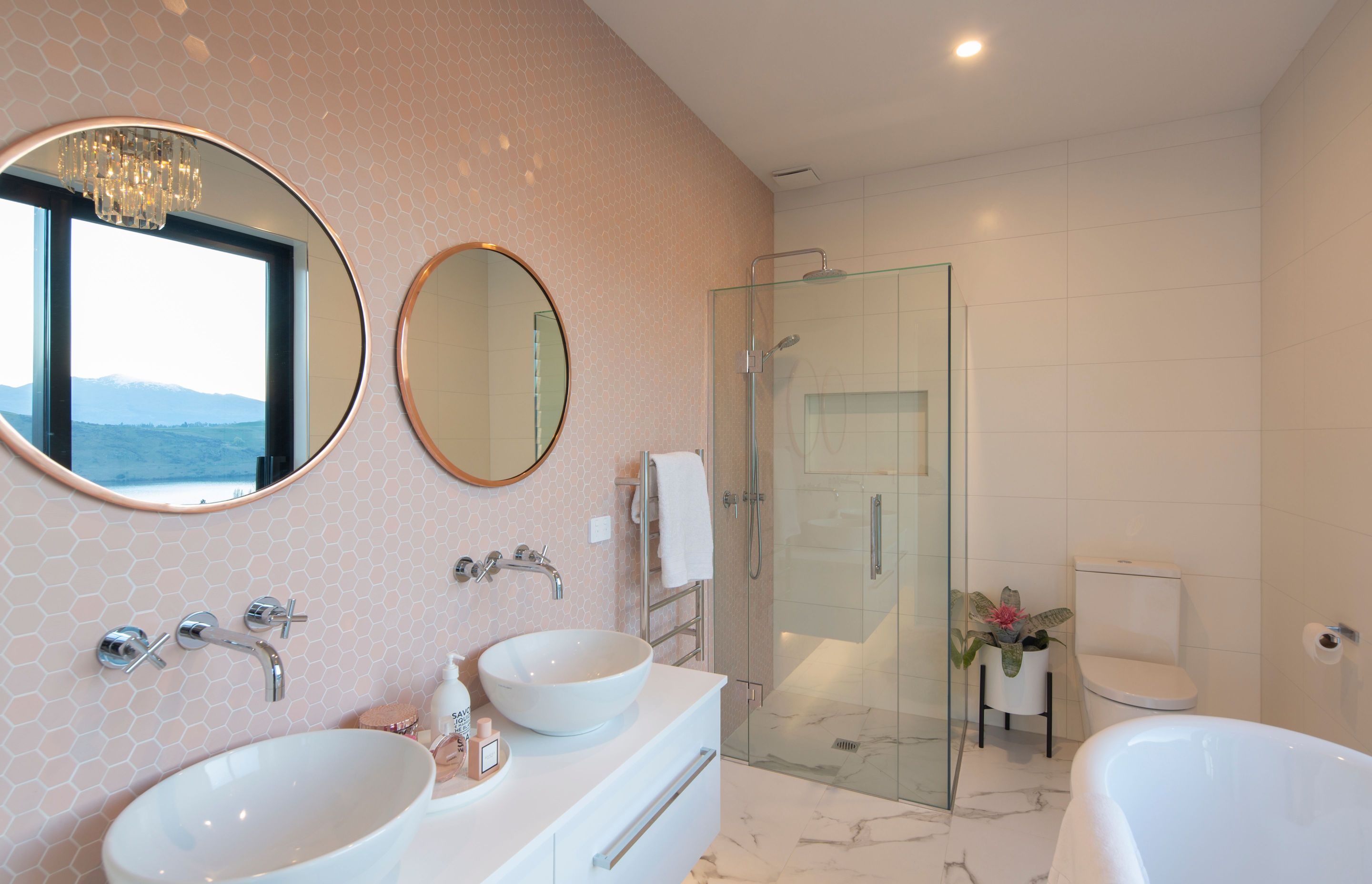 Beautifully feminine guest bathroom with blush beehive feature wall and marble floor tiles from Flooring Xtra.