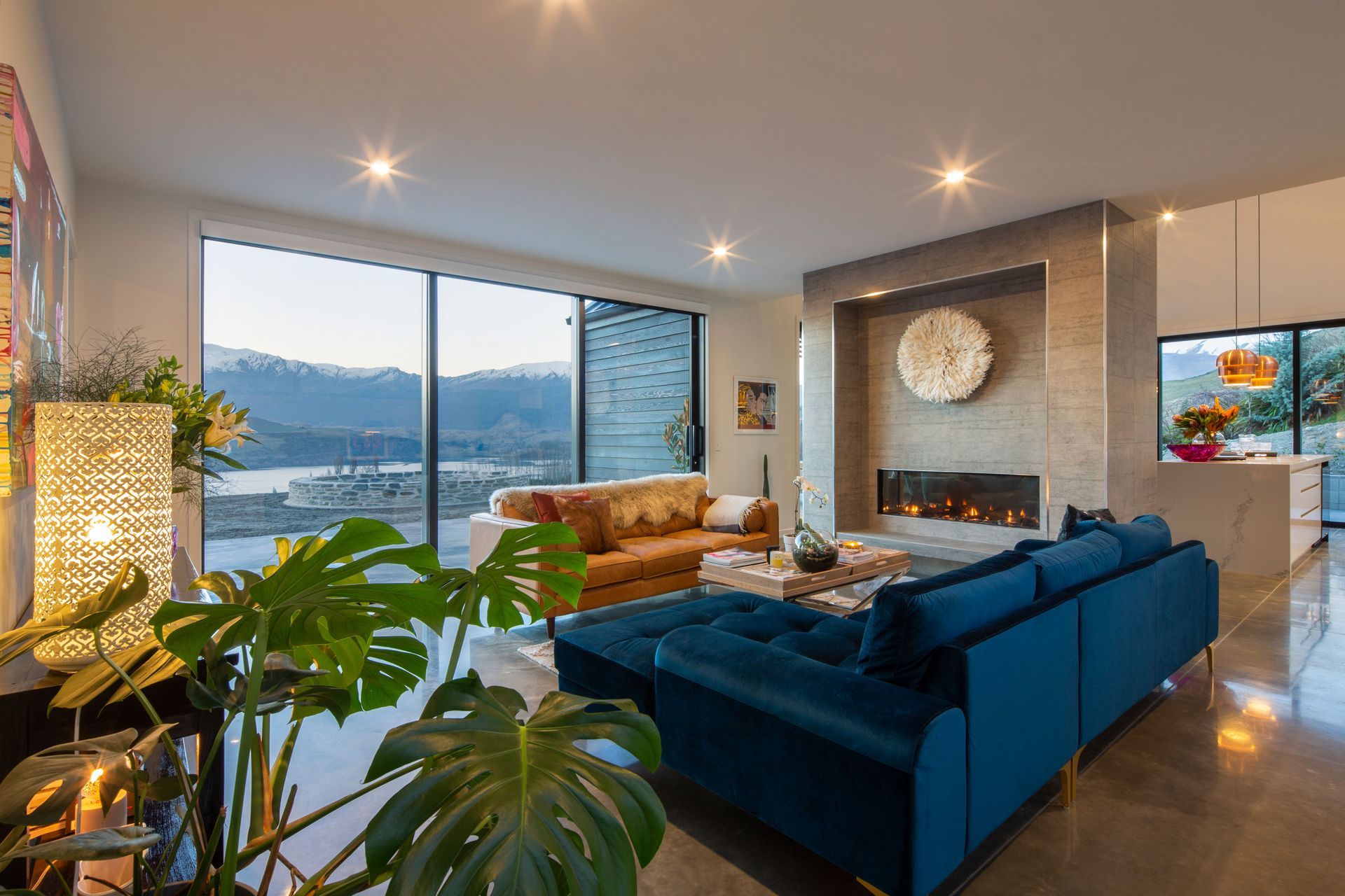 Fireplace clad in concrete tiles to echo the concrete floors that are float polished. Jewel coloured velvet couch from Me & My Trend.