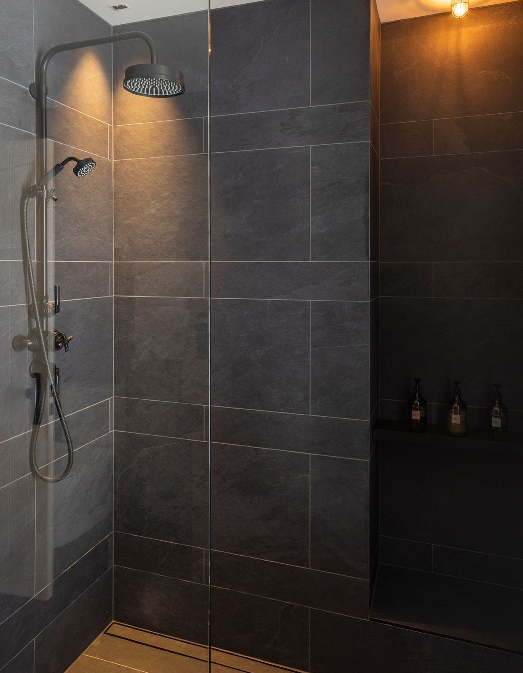 Black textured tile in the bathrooms contrasts with white board and batten that is used in the hallways.