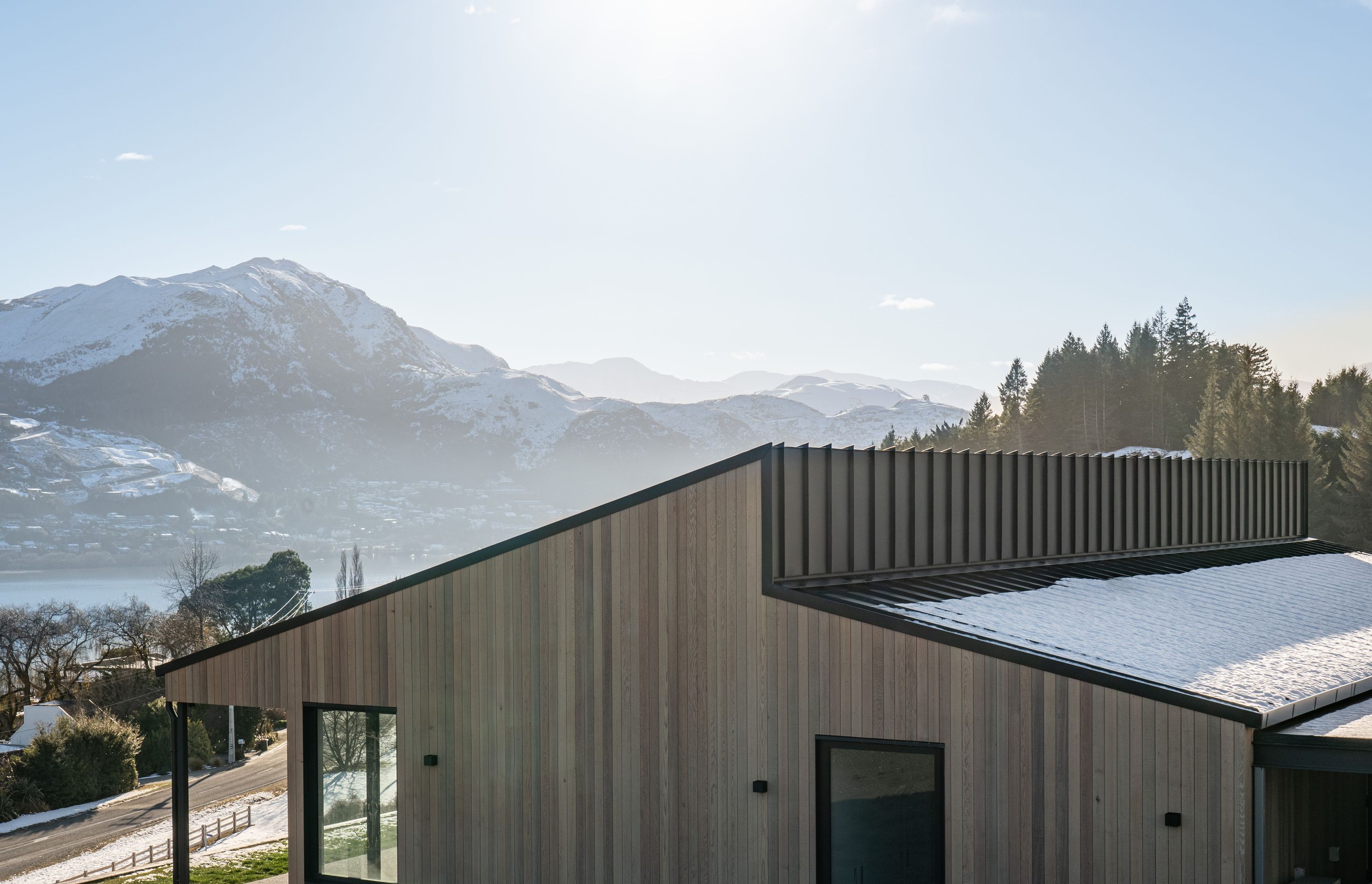 The clean, folded geometry of the roofline informs a hierarchy of spaces within and also extends beyond the building envelope to create porch enclosures that frame various views of the lake and mountains.