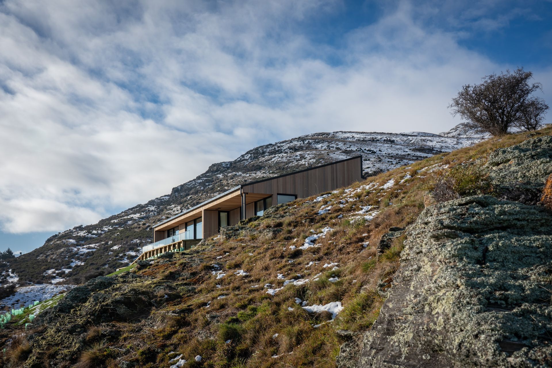 The monopitch roofline mimics the slope of the surrounding topography serving to bed the structure into the landscape while the use of cedar cladding matches the tones of the rocks and grasses.