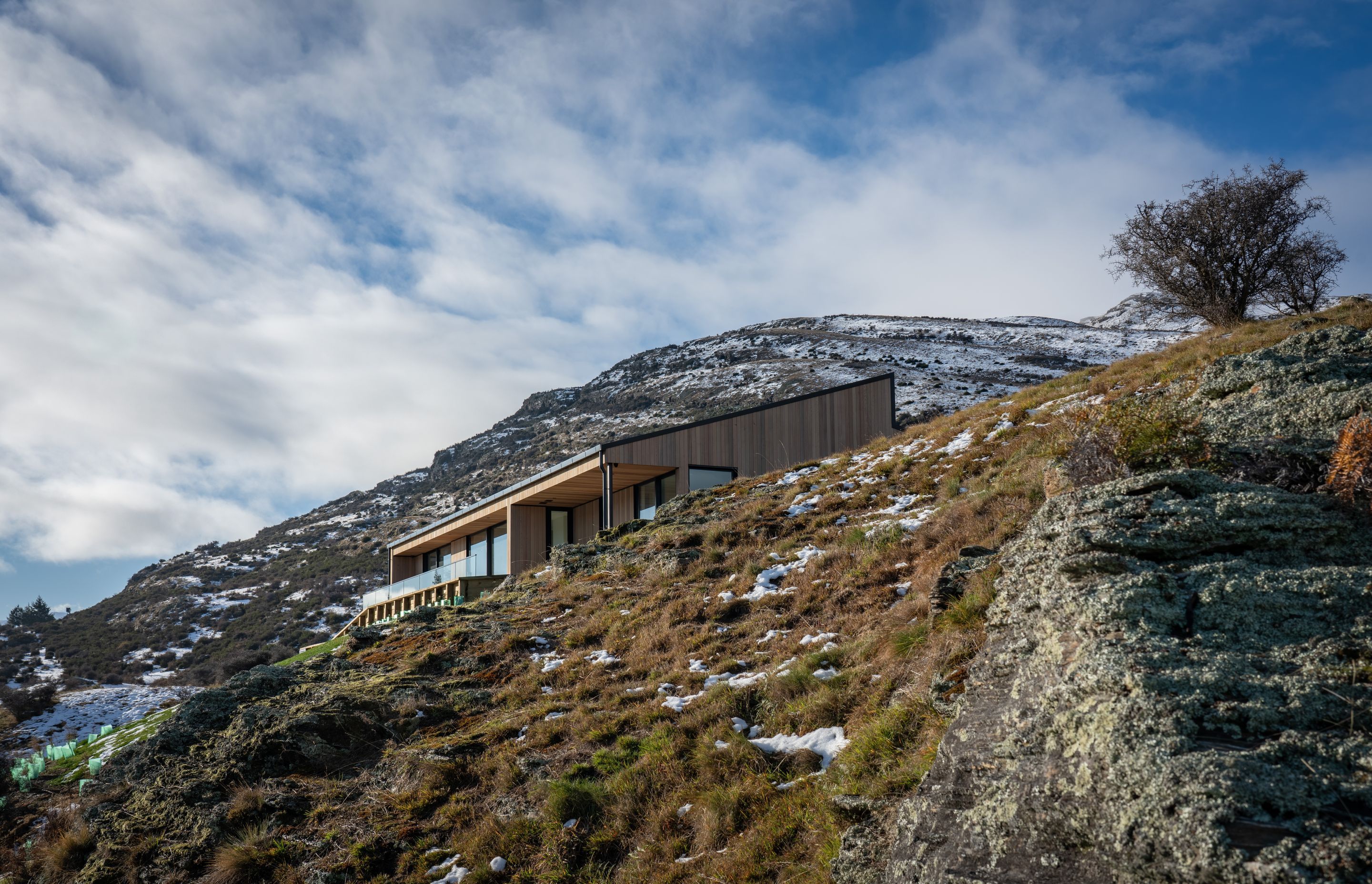 The monopitch roofline mimics the slope of the surrounding topography serving to bed the structure into the landscape while the use of cedar cladding matches the tones of the rocks and grasses.