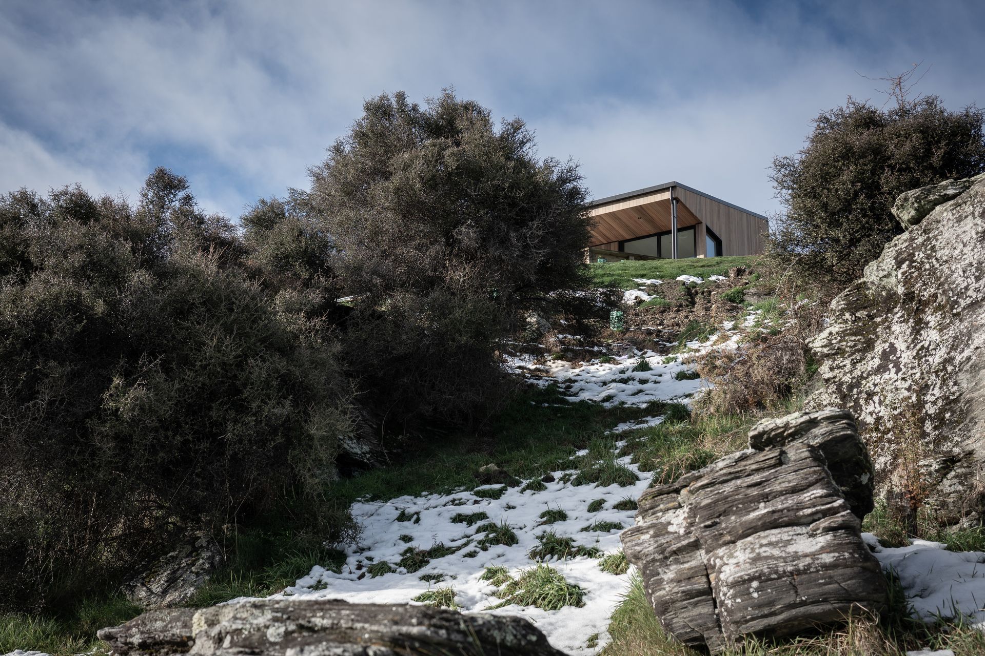 The site, which is rocky and sloping, largely informed the footprint and size of the house resulting in a compact design incorporating living areas to the north and service areas to the south.