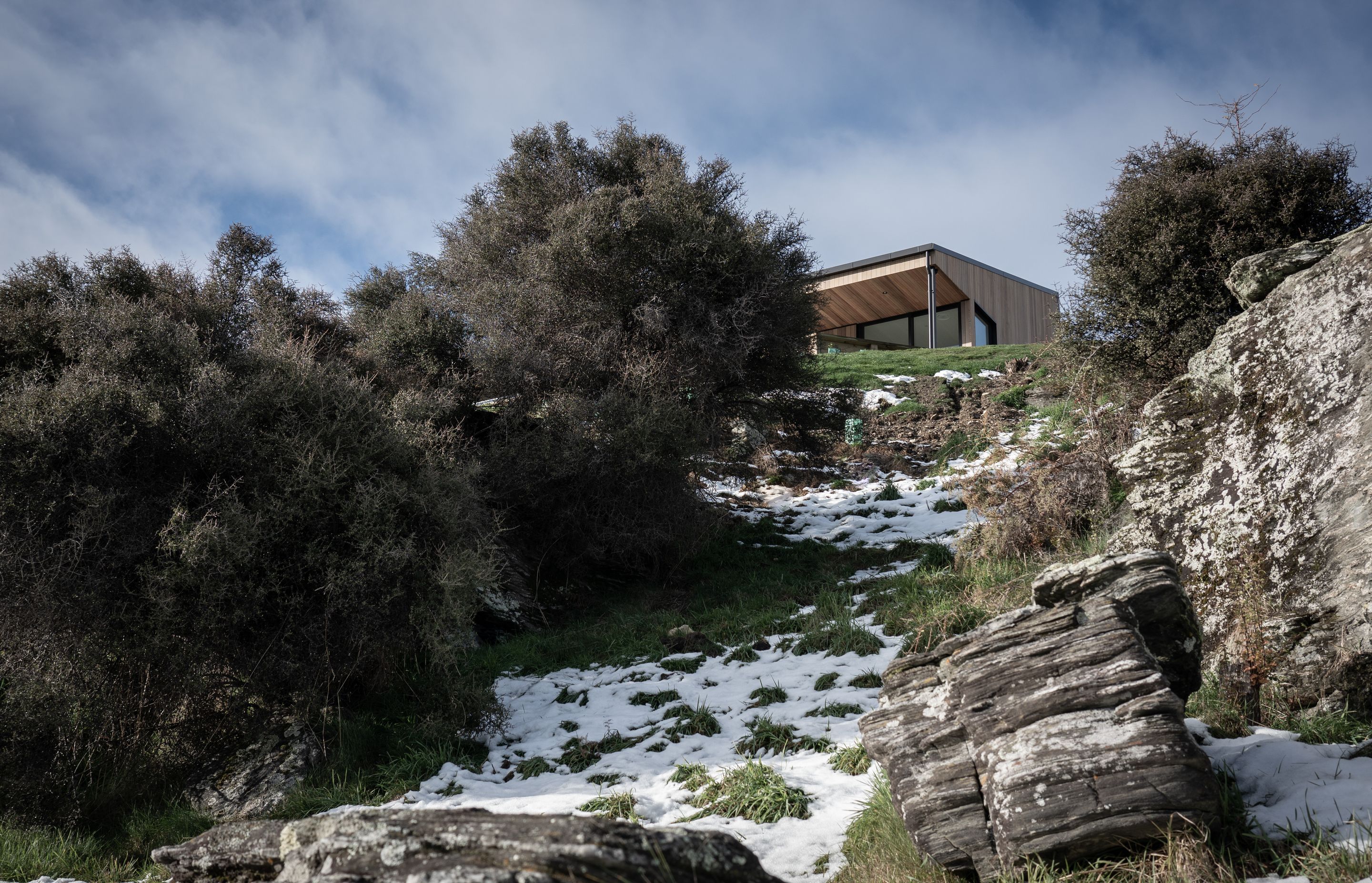 The site, which is rocky and sloping, largely informed the footprint and size of the house resulting in a compact design incorporating living areas to the north and service areas to the south.