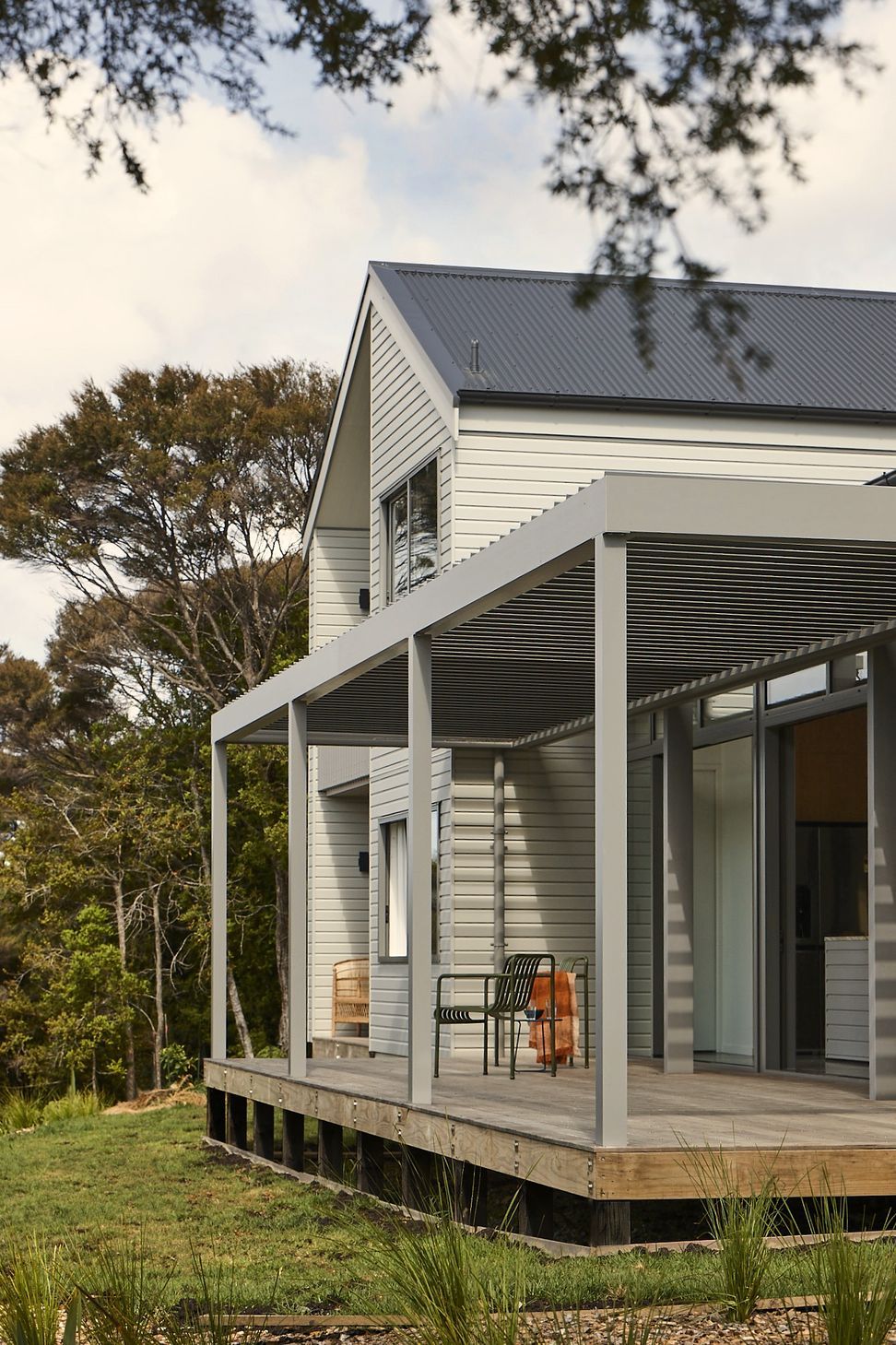 Viewed from the garden, the home's simple architectural form sits comfortably within the landscape. The pergola-covered deck extends the living spaces outdoors, while the separate bedroom and living wings express the home's distinctive planning.